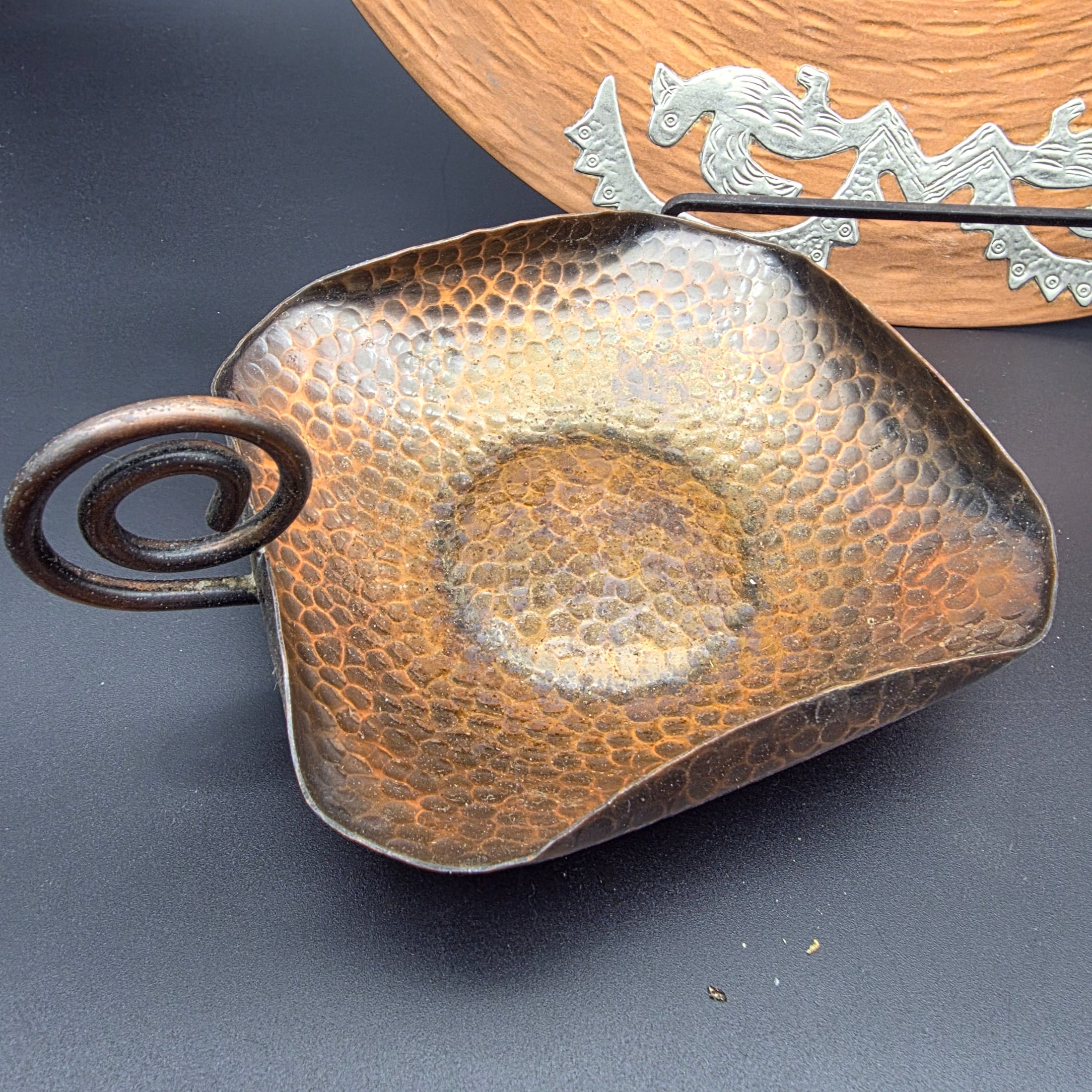 A diverse collection of vintage metalware, including a large copper wall plaque, a hammered copper dish, a small brass plate, two small brass cups, and a bronze/copper vase. - View 8