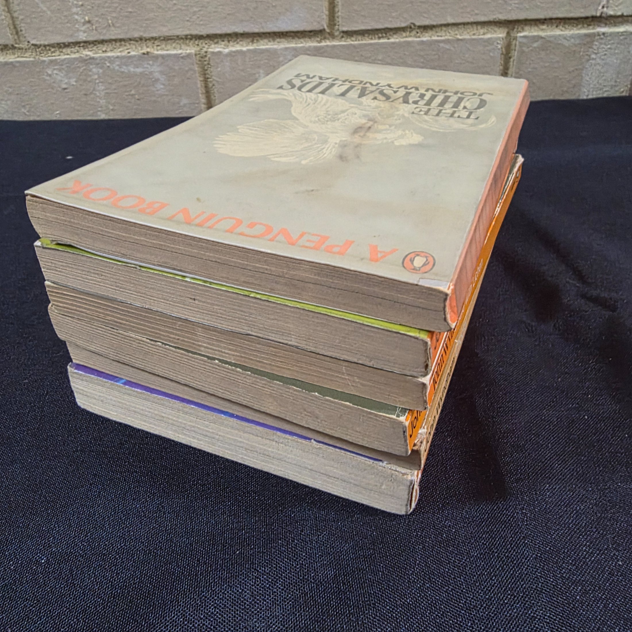 A collection of six vintage paperback science fiction novels by John Wyndham, featuring classic Penguin cover art. - View 5