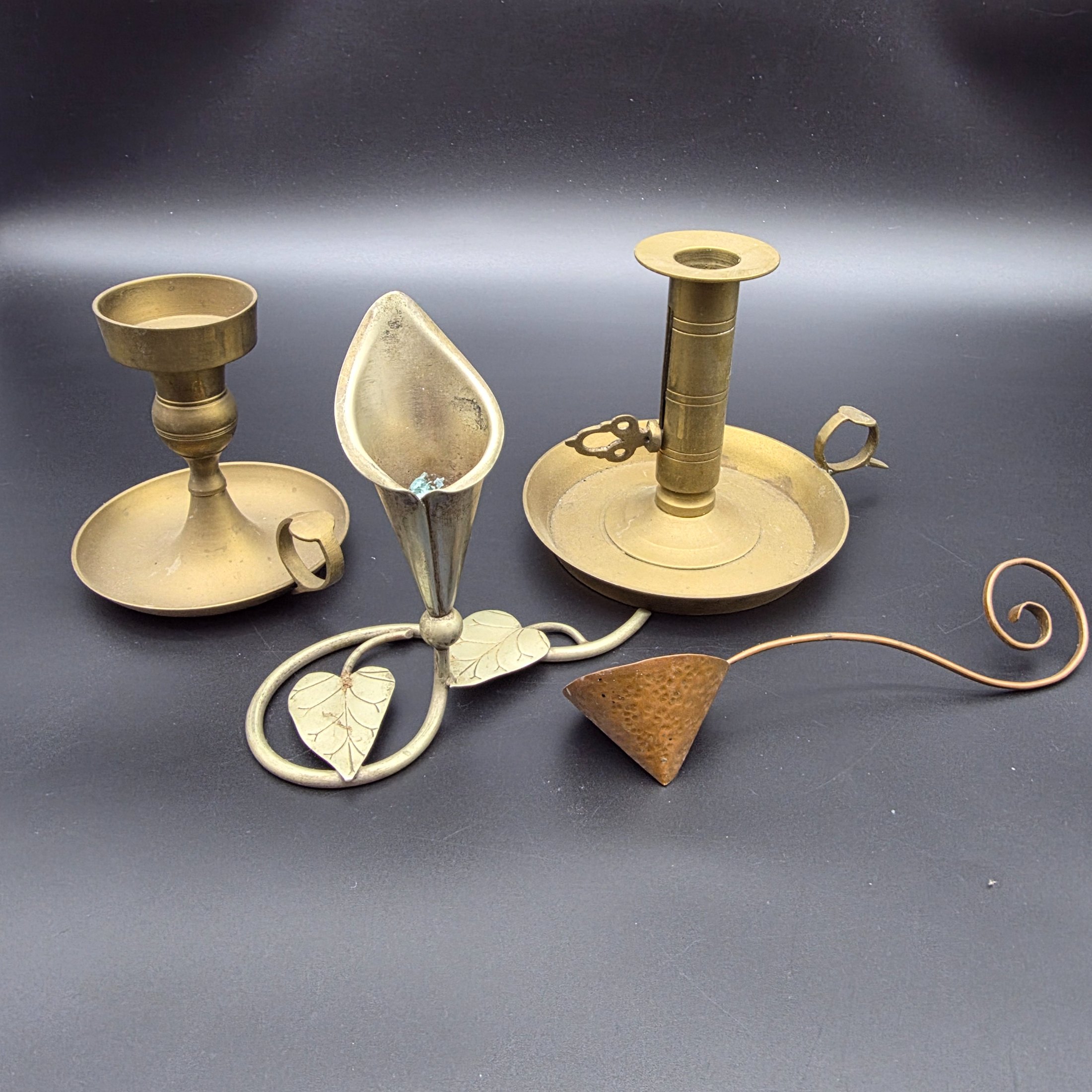 A lot of vintage brass and copper candle accessories, including two candlesticks and a decorative taper holder with an attached snuffer, likely dating from the early to mid-20th century.