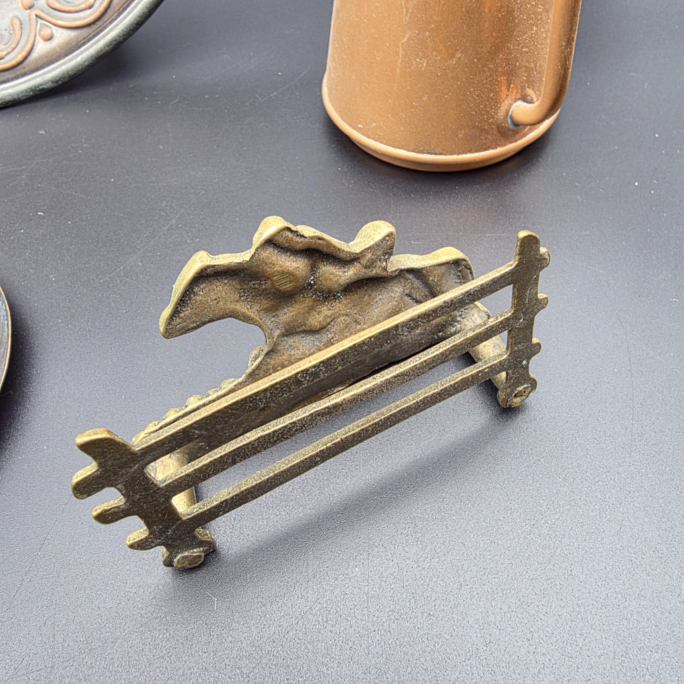 A curated collection of vintage metallic decorative sundries, primarily crafted from brass and copper, spanning mid to late 20th-century origins, including an embossed wall plate, a plant mister, letter holder, ashtrays, a vase, and a small dish. - View 5