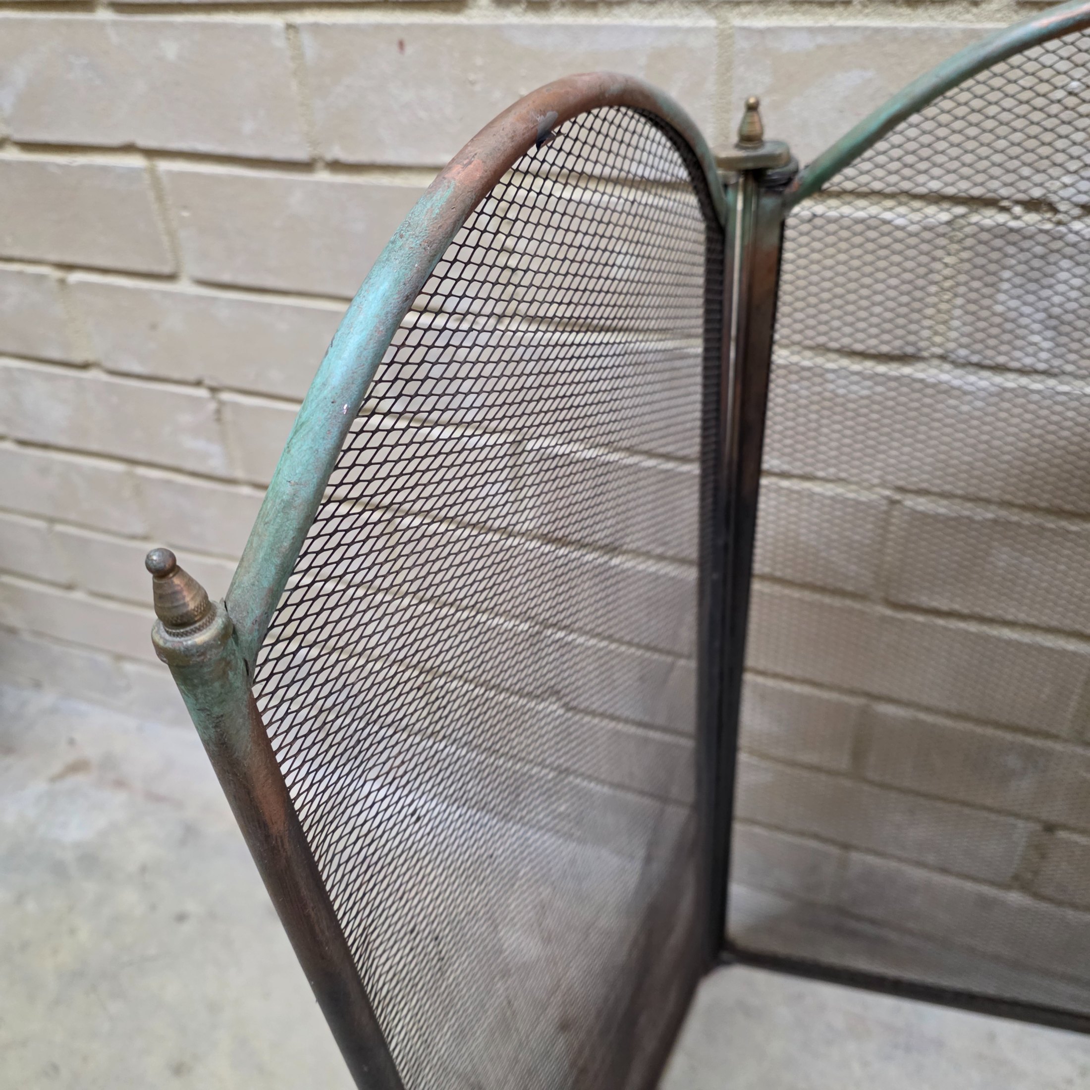 A vintage four-panel brass and mesh fireplace screen, designed to protect from sparks while adding decorative appeal to a hearth. - View 2