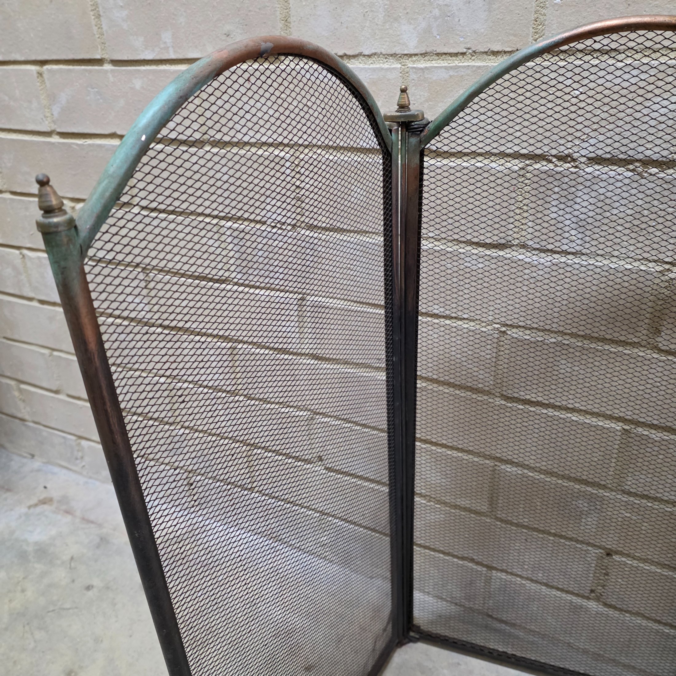 A vintage four-panel brass and mesh fireplace screen, designed to protect from sparks while adding decorative appeal to a hearth. - View 4