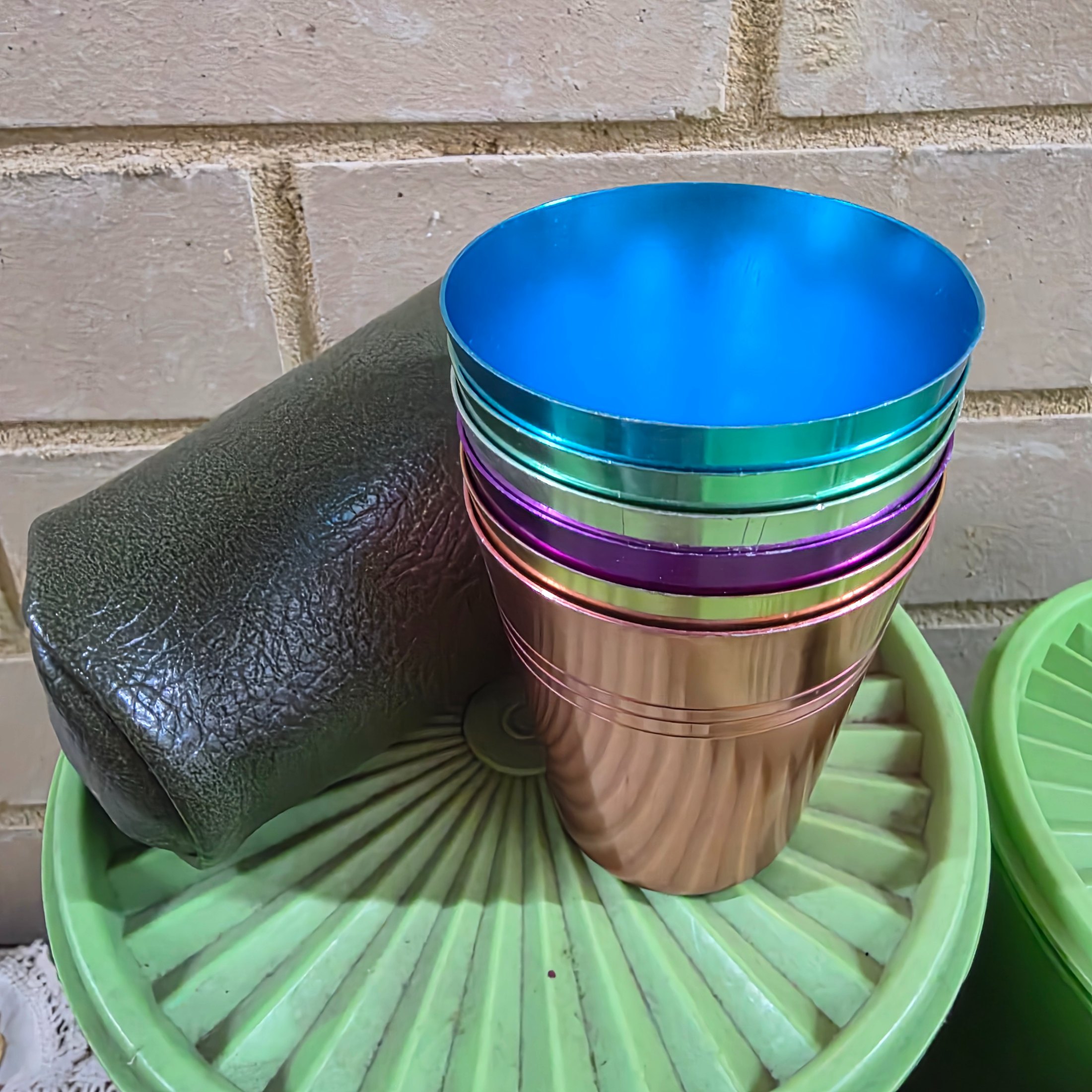 A diverse collection of vintage homewares and kitchen items including cast iron pans, a hand mixer, Tupperware, ceramic crocks, aluminium cups, and various other utensils and decorative pieces. - View 2