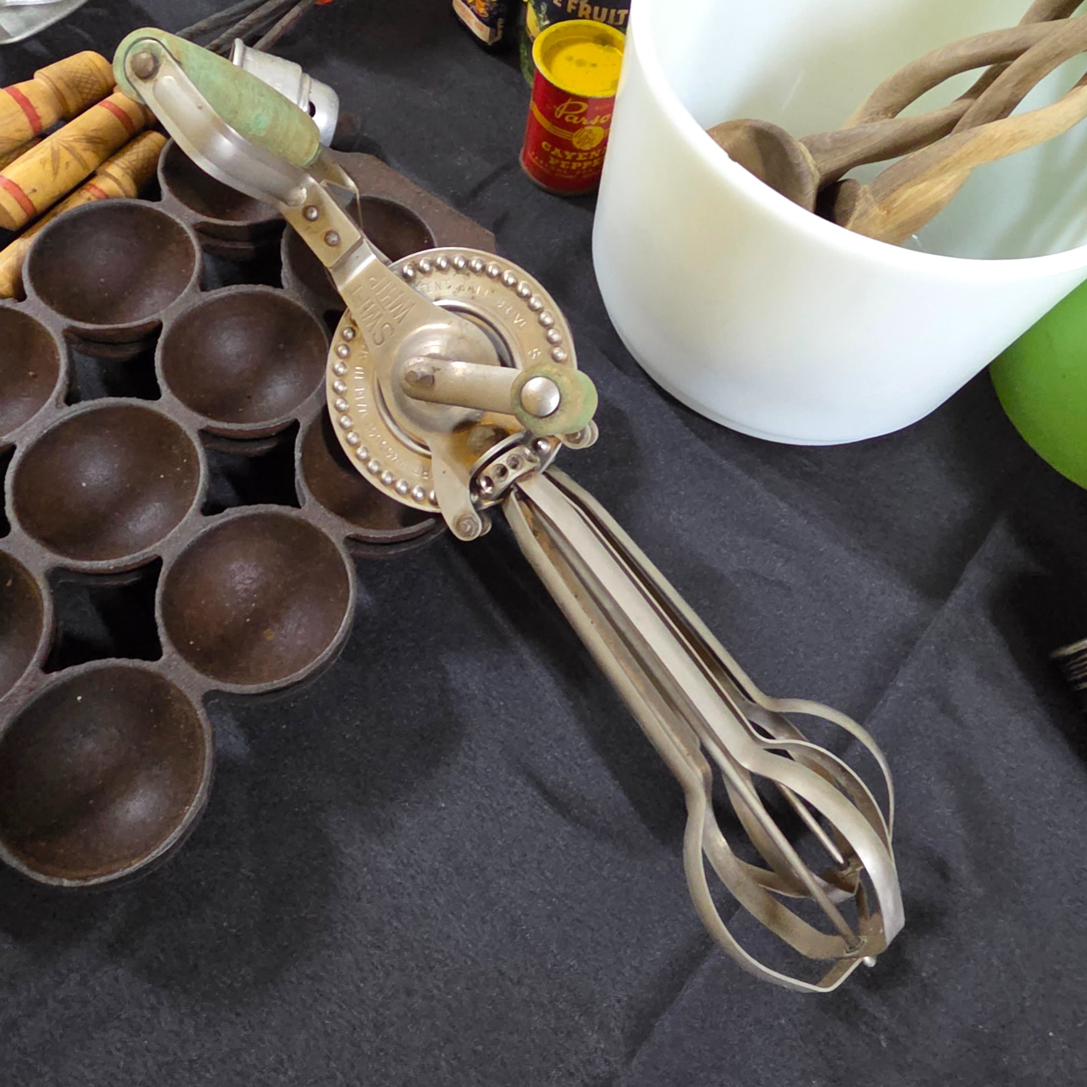 A diverse collection of vintage homewares and kitchen items including cast iron pans, a hand mixer, Tupperware, ceramic crocks, aluminium cups, and various other utensils and decorative pieces. - View 7