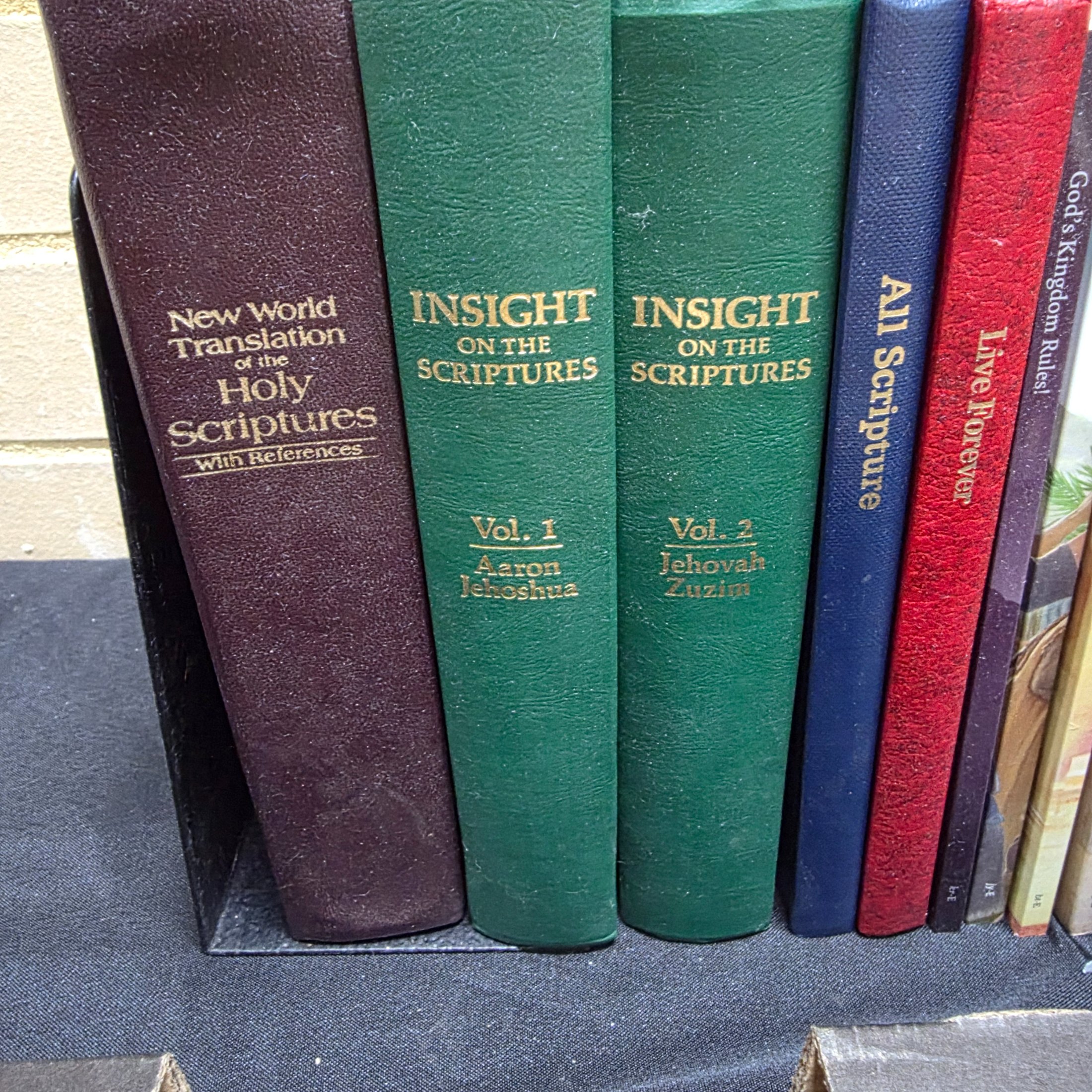 A large collection of mixed religious books and Bibles, including various translations, study guides, and annual publications, presented in a cardboard box and arranged on a surface. - View 2