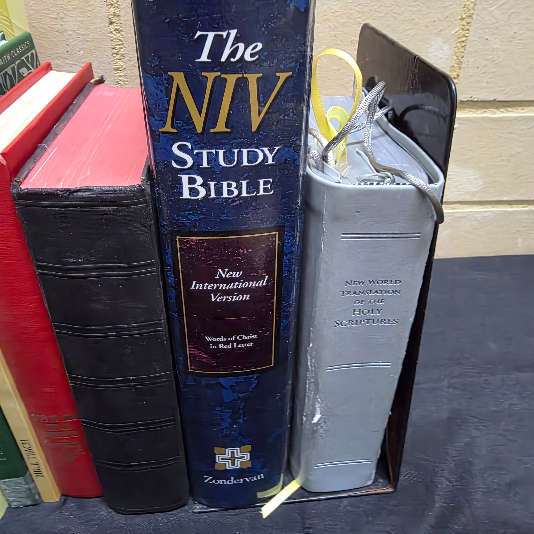 A large collection of mixed religious books and Bibles, including various translations, study guides, and annual publications, presented in a cardboard box and arranged on a surface. - View 4