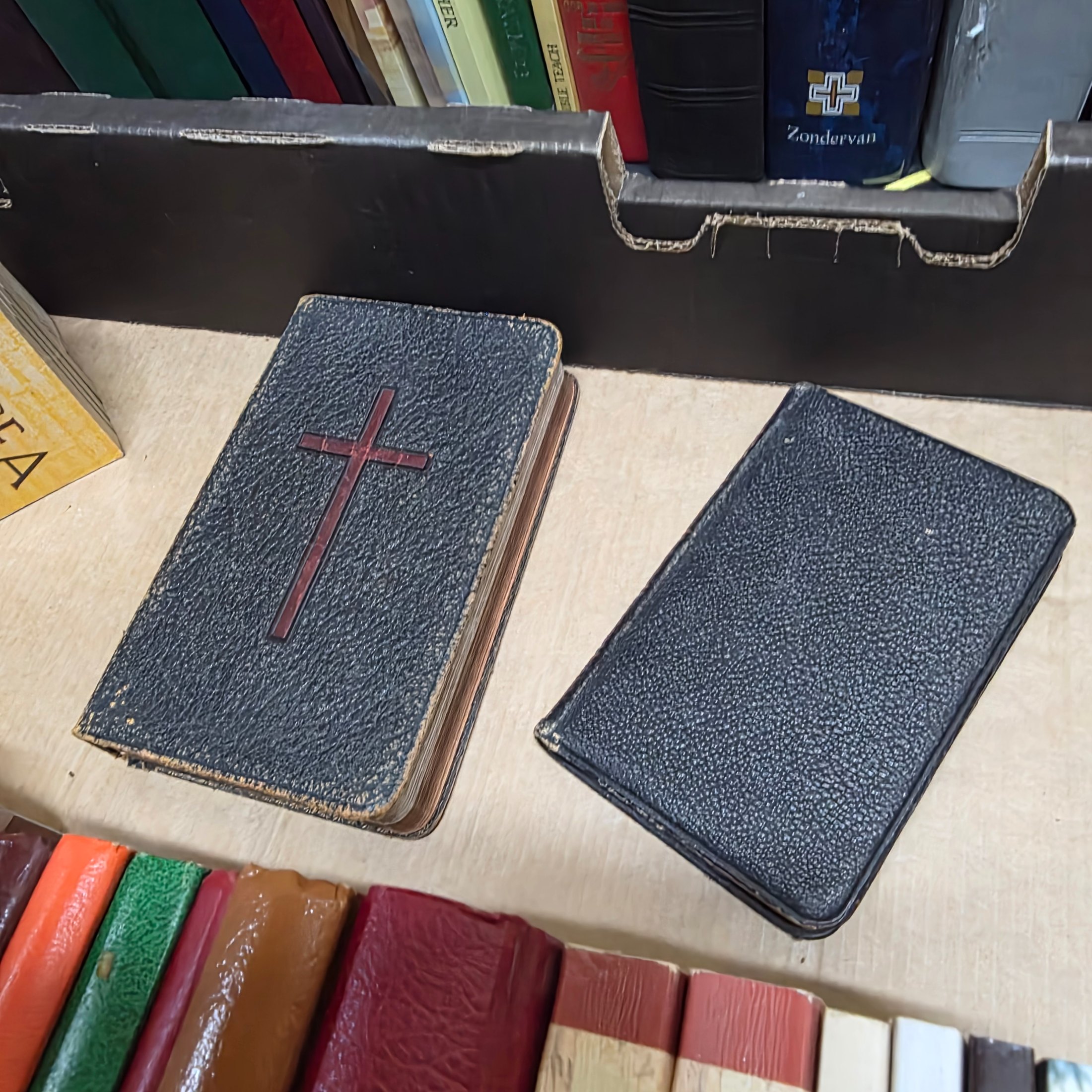 A large collection of mixed religious books and Bibles, including various translations, study guides, and annual publications, presented in a cardboard box and arranged on a surface. - View 6