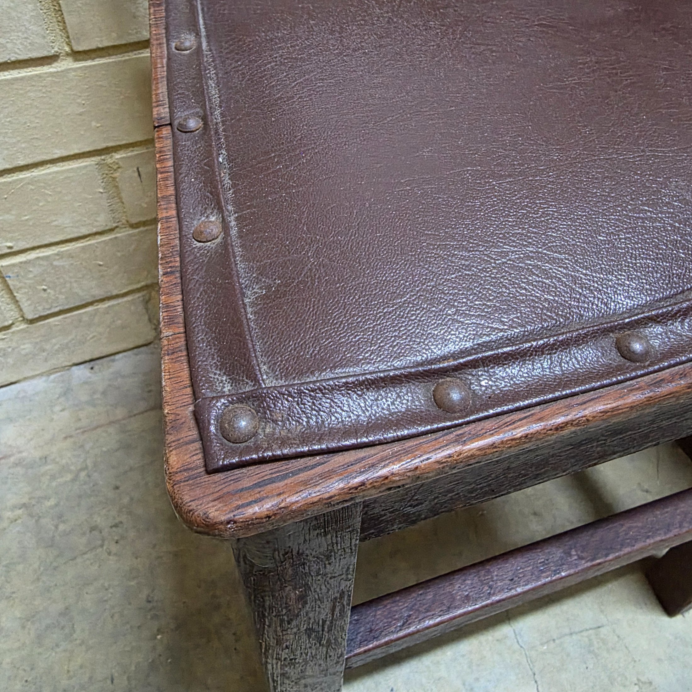 A set of four vintage dark wood dining chairs, featuring a simple, robust design and dark brown studded faux leather seats. - View 3