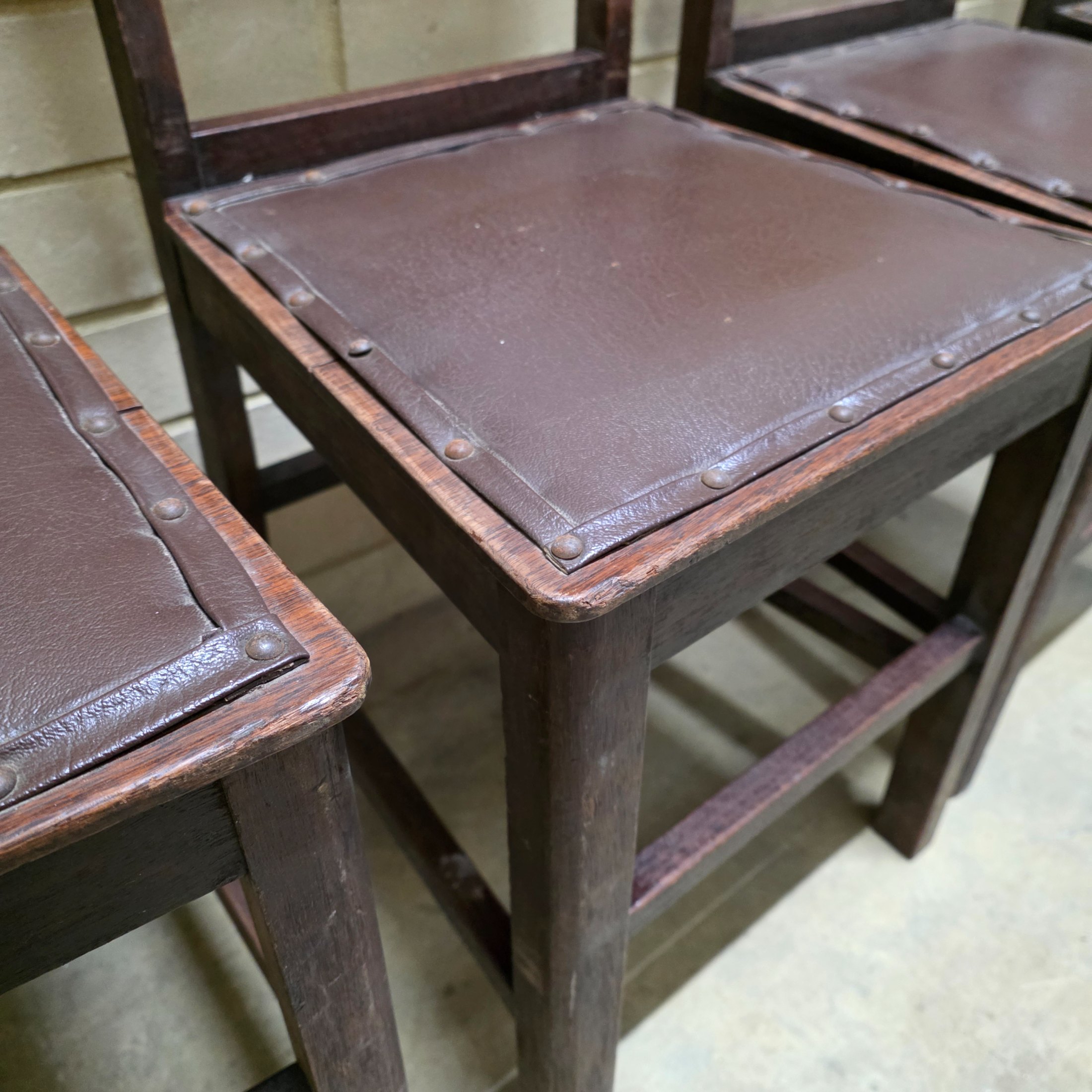 A set of four vintage dark wood dining chairs, featuring a simple, robust design and dark brown studded faux leather seats. - View 5