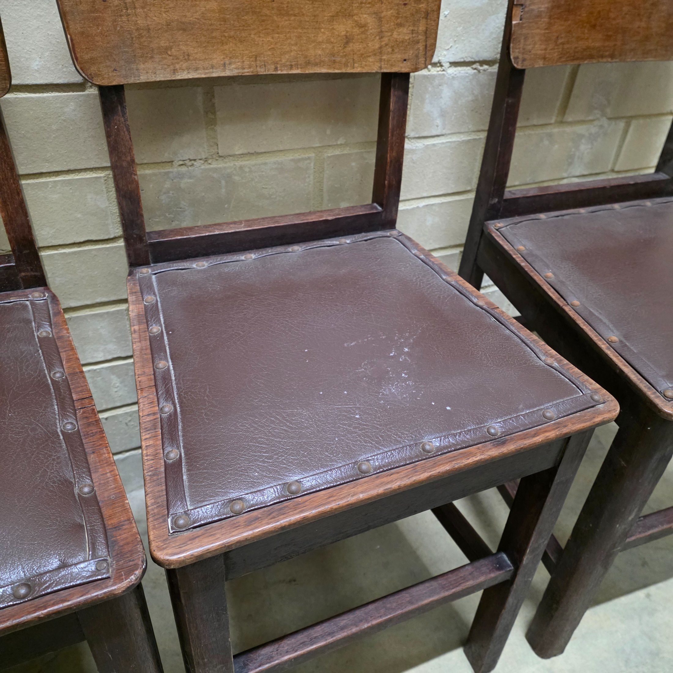 A set of four vintage dark wood dining chairs, featuring a simple, robust design and dark brown studded faux leather seats. - View 6