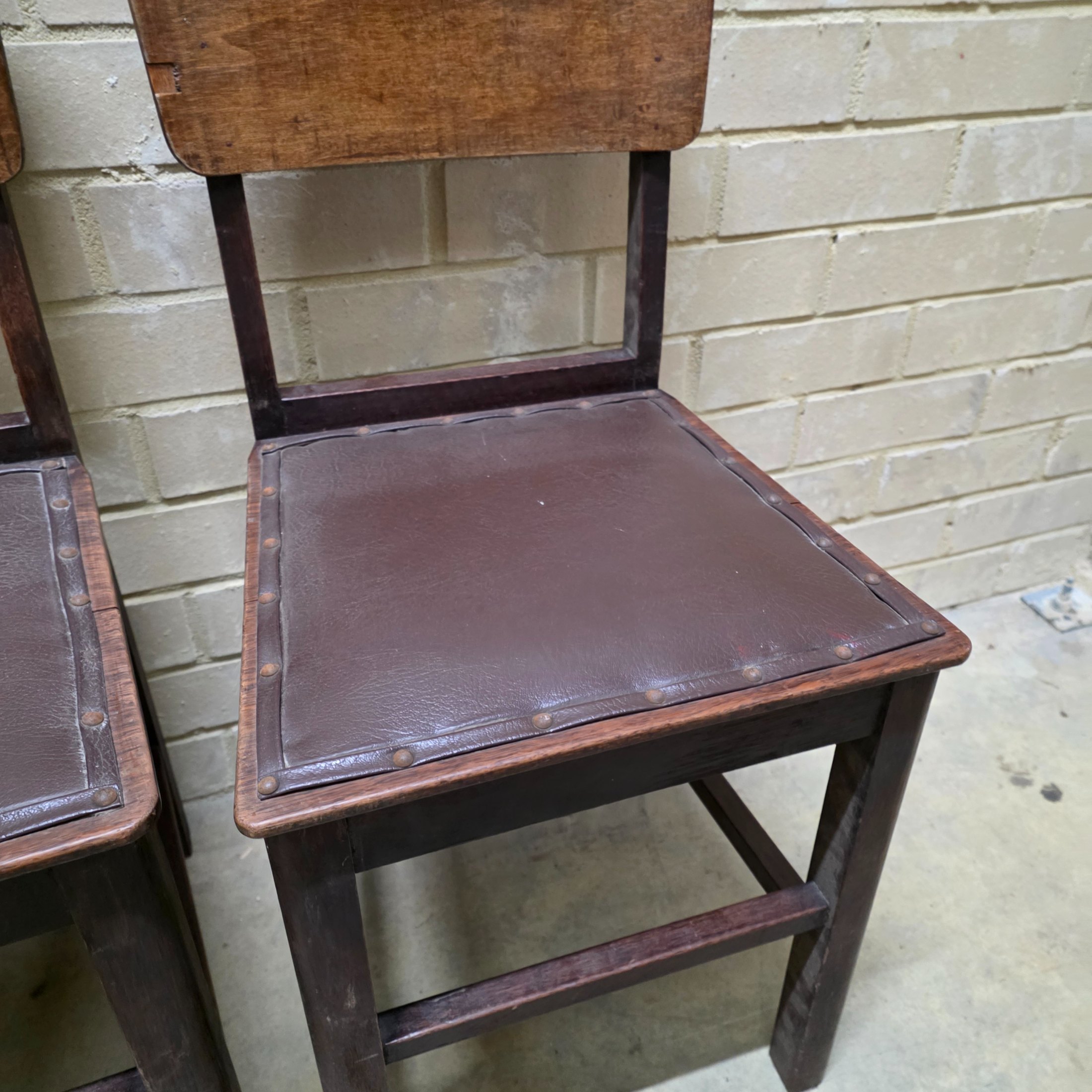 A set of four vintage dark wood dining chairs, featuring a simple, robust design and dark brown studded faux leather seats. - View 7
