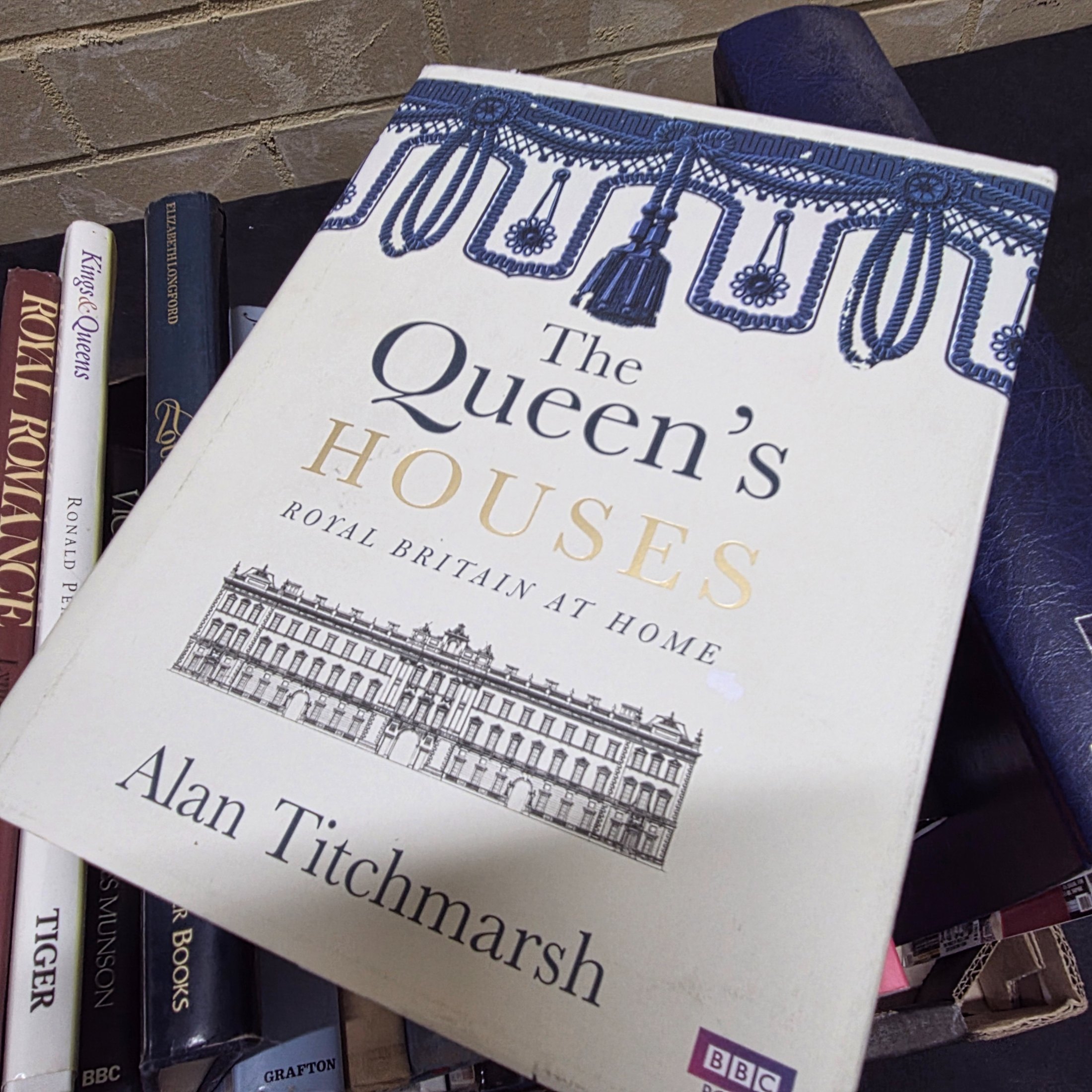 A cardboard box filled with approximately two dozen assorted books primarily focused on British royalty, including biographies of Princess Diana and historical accounts of castles and queens. - View 8