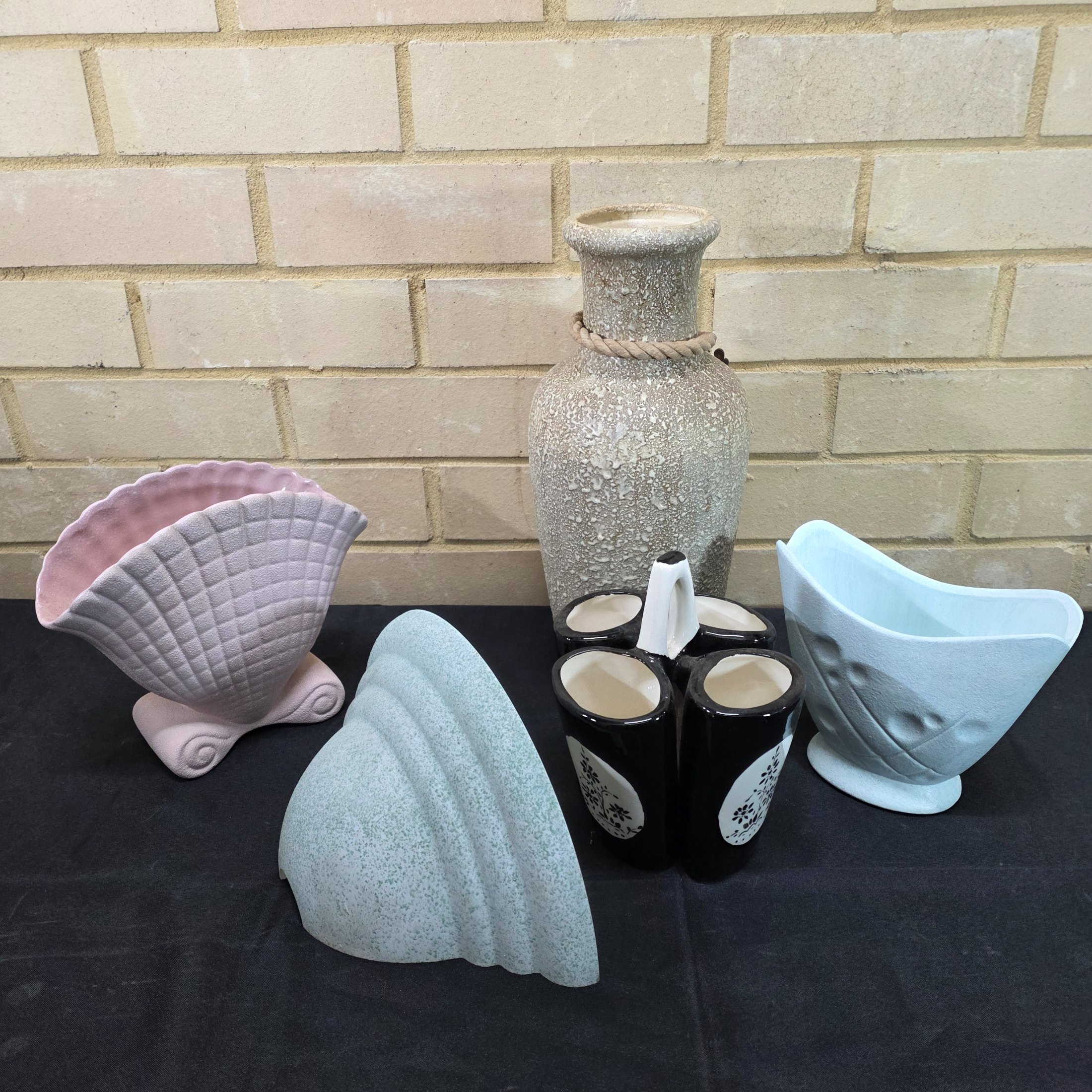 A collection of vintage Australian ceramic sundries, including a textured Micasa vase with rope, a pink Raynham shell-shaped vase, a light blue Surrey vase, a black and white condiment holder, and a light green shell-like decorative piece.