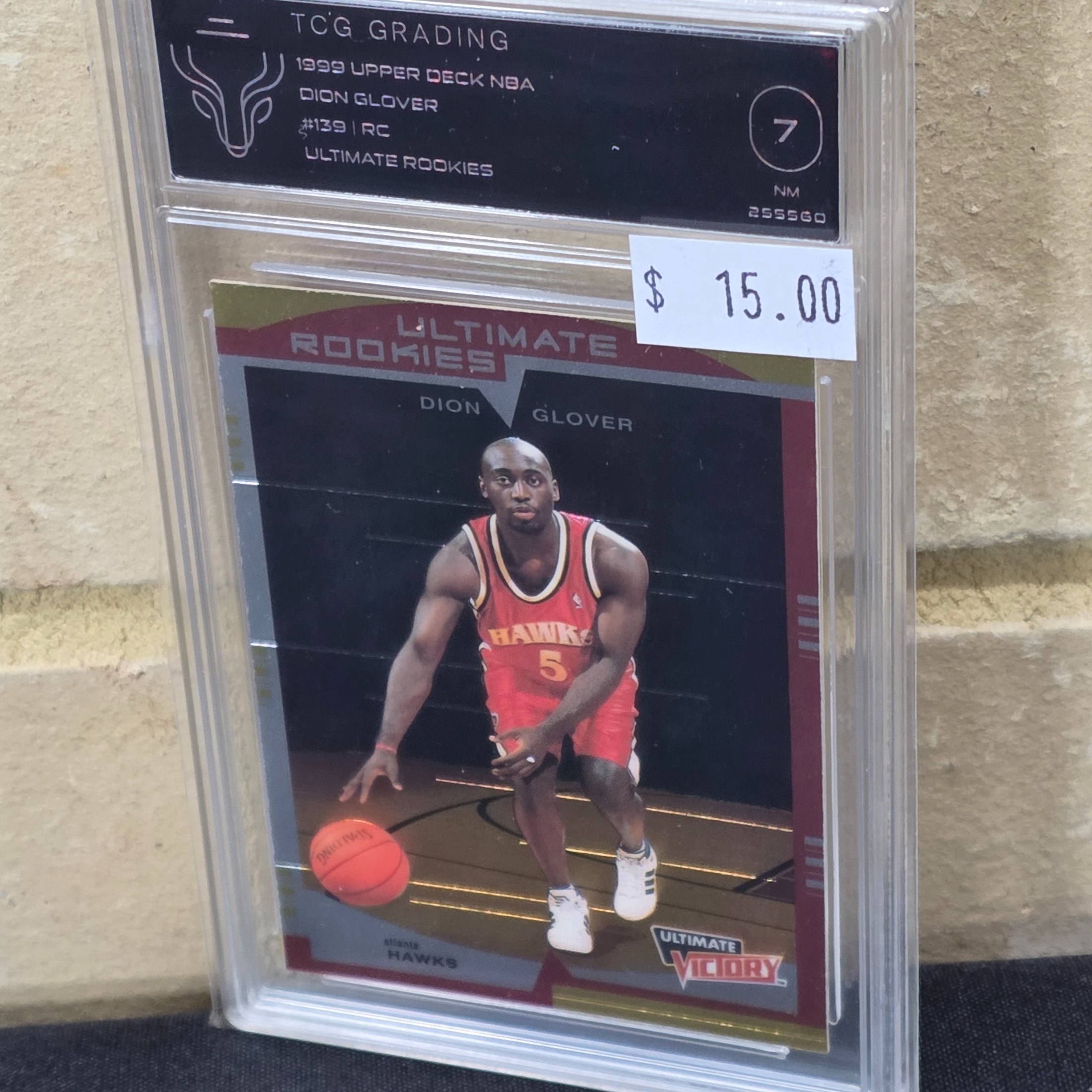 A 1999 Upper Deck NBA basketball rookie card of Dion Glover, graded 7 NM by TCG Grading, encapsulated in a protective slab.
