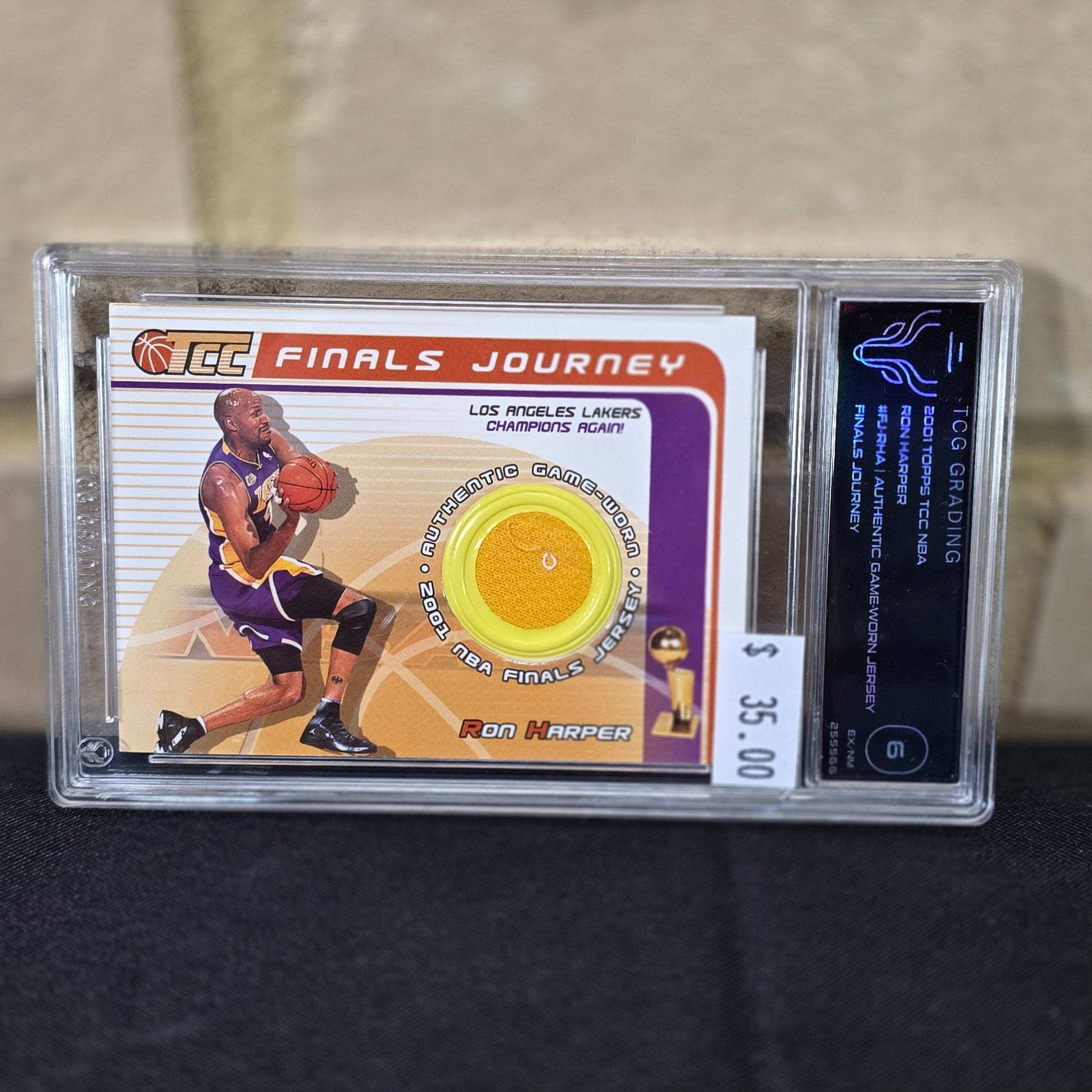 A 2001 Topps NBA Finals Journey graded trading card featuring Ron Harper with an authentic game-worn jersey swatch, encapsulated in a TCG Grading slab.