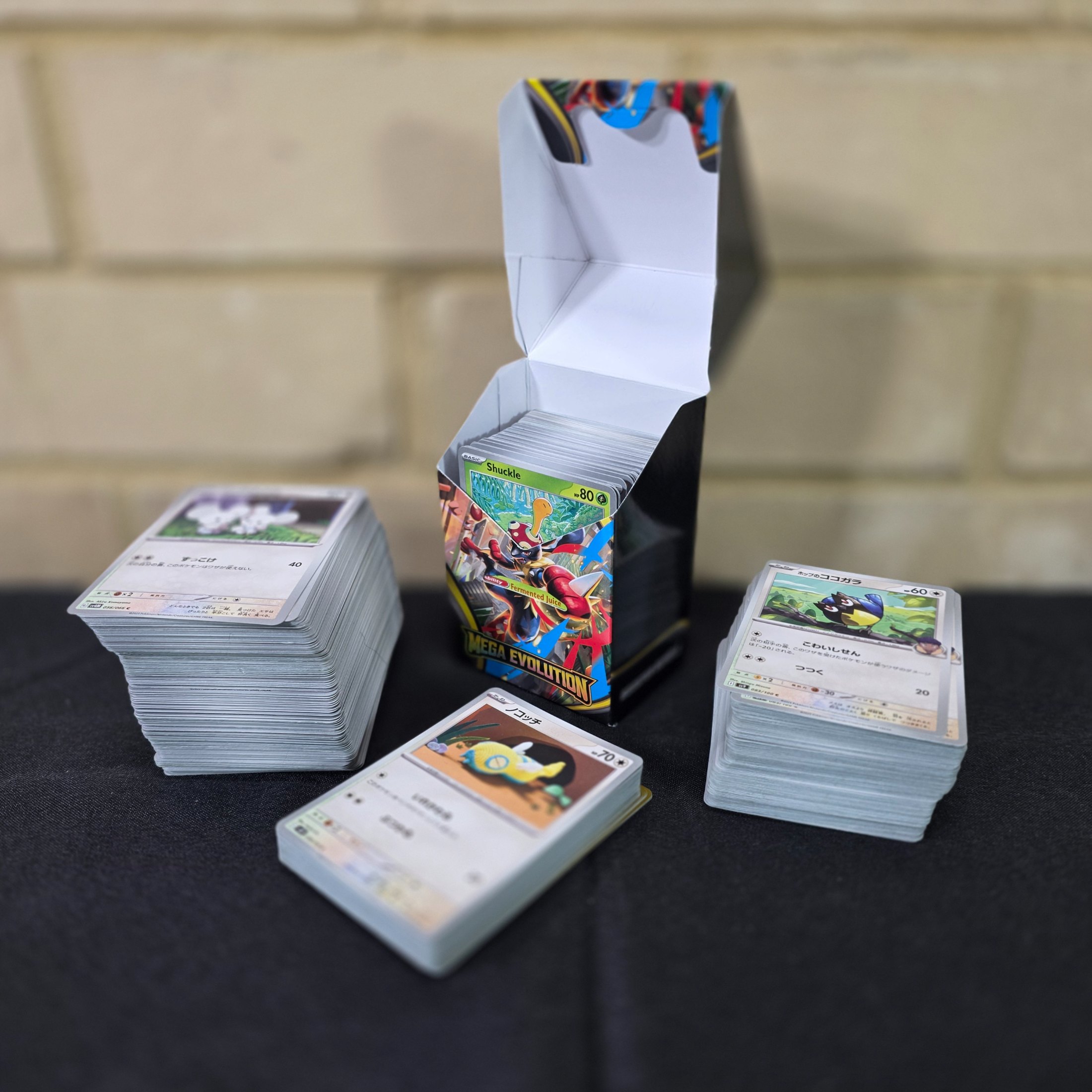 A collection of Japanese Pokémon Trading Card Game cards, including a "Mega Evolution" themed box and multiple stacks of cards.