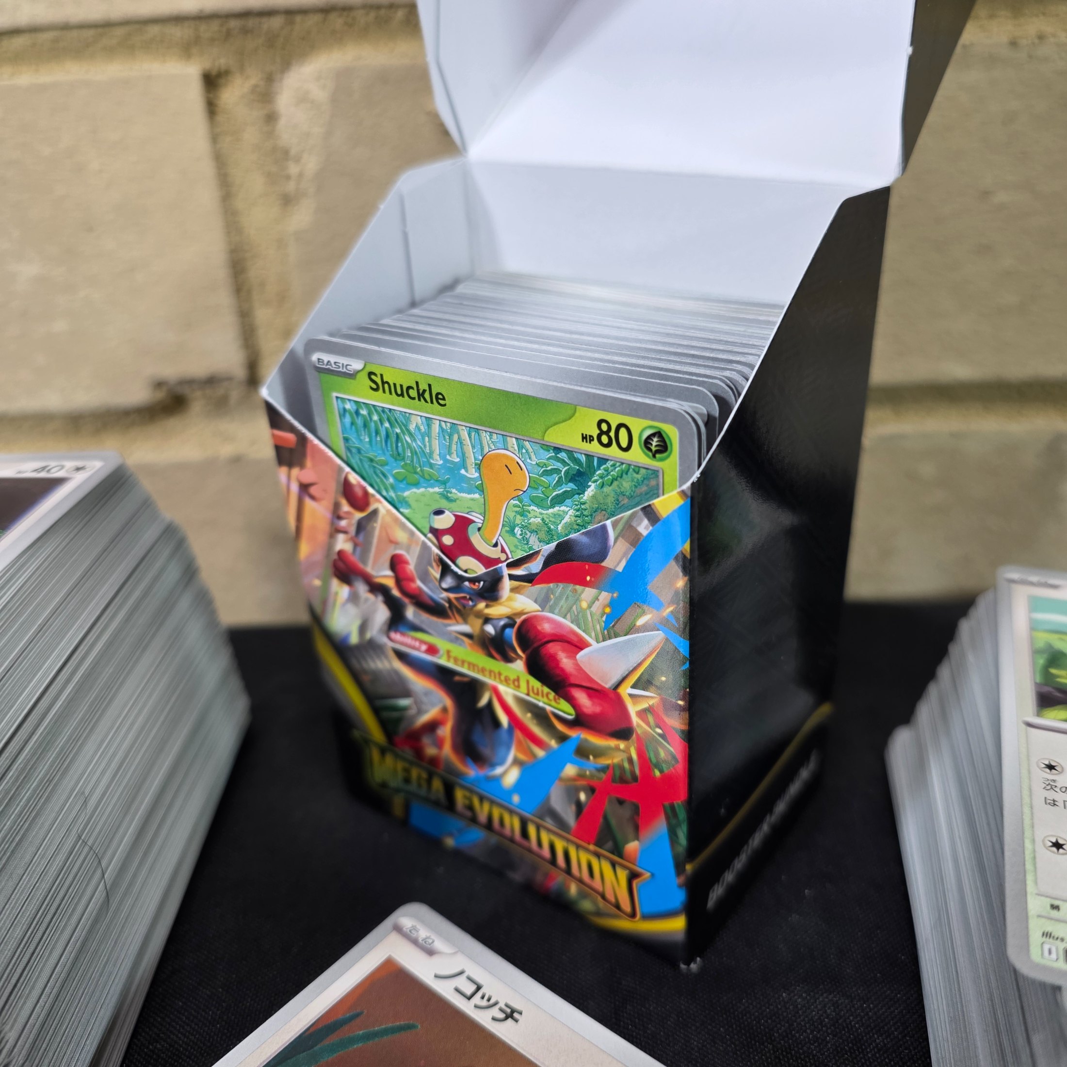 A collection of Japanese Pokémon Trading Card Game cards, including a "Mega Evolution" themed box and multiple stacks of cards. - View 2
