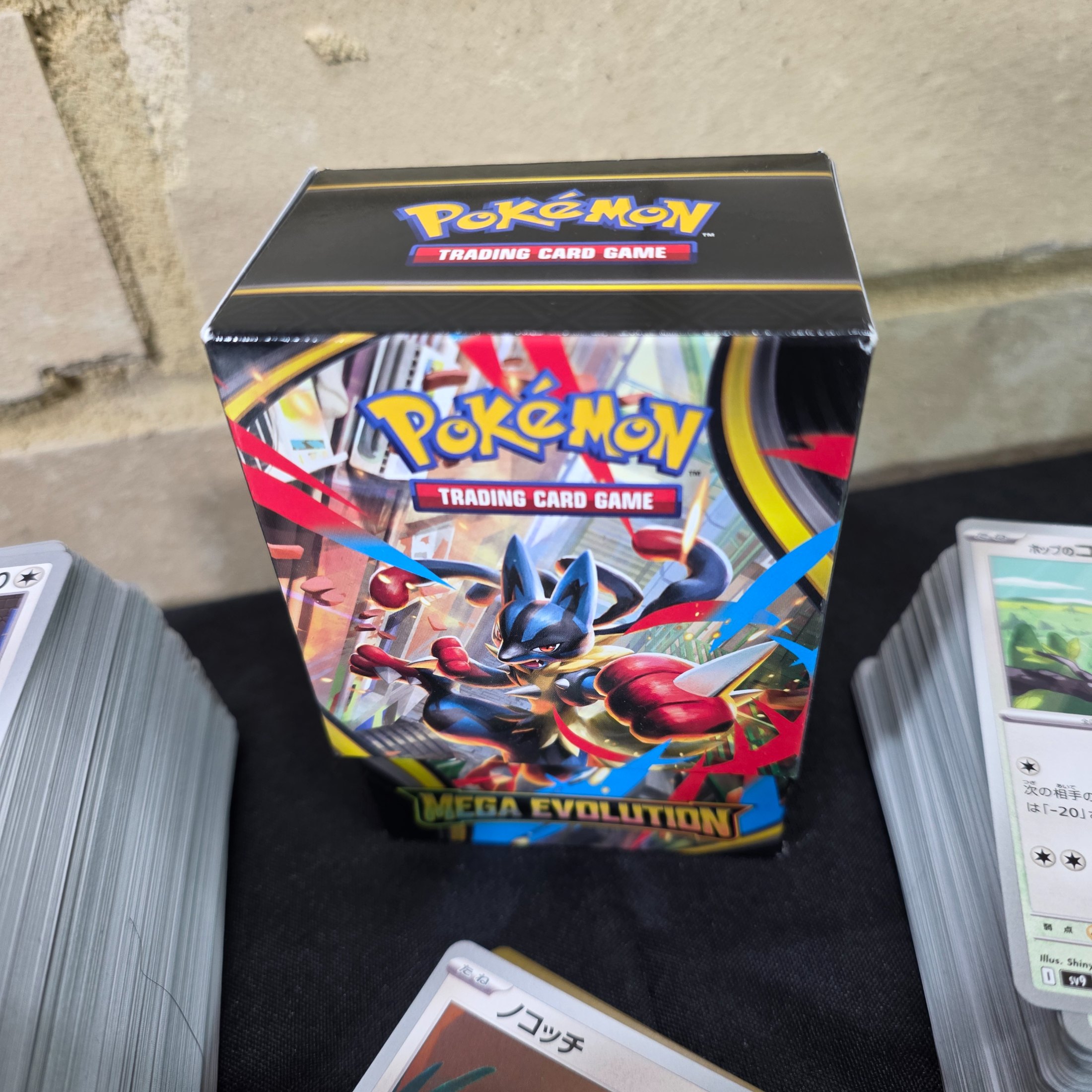 A collection of Japanese Pokémon Trading Card Game cards, including a "Mega Evolution" themed box and multiple stacks of cards. - View 3