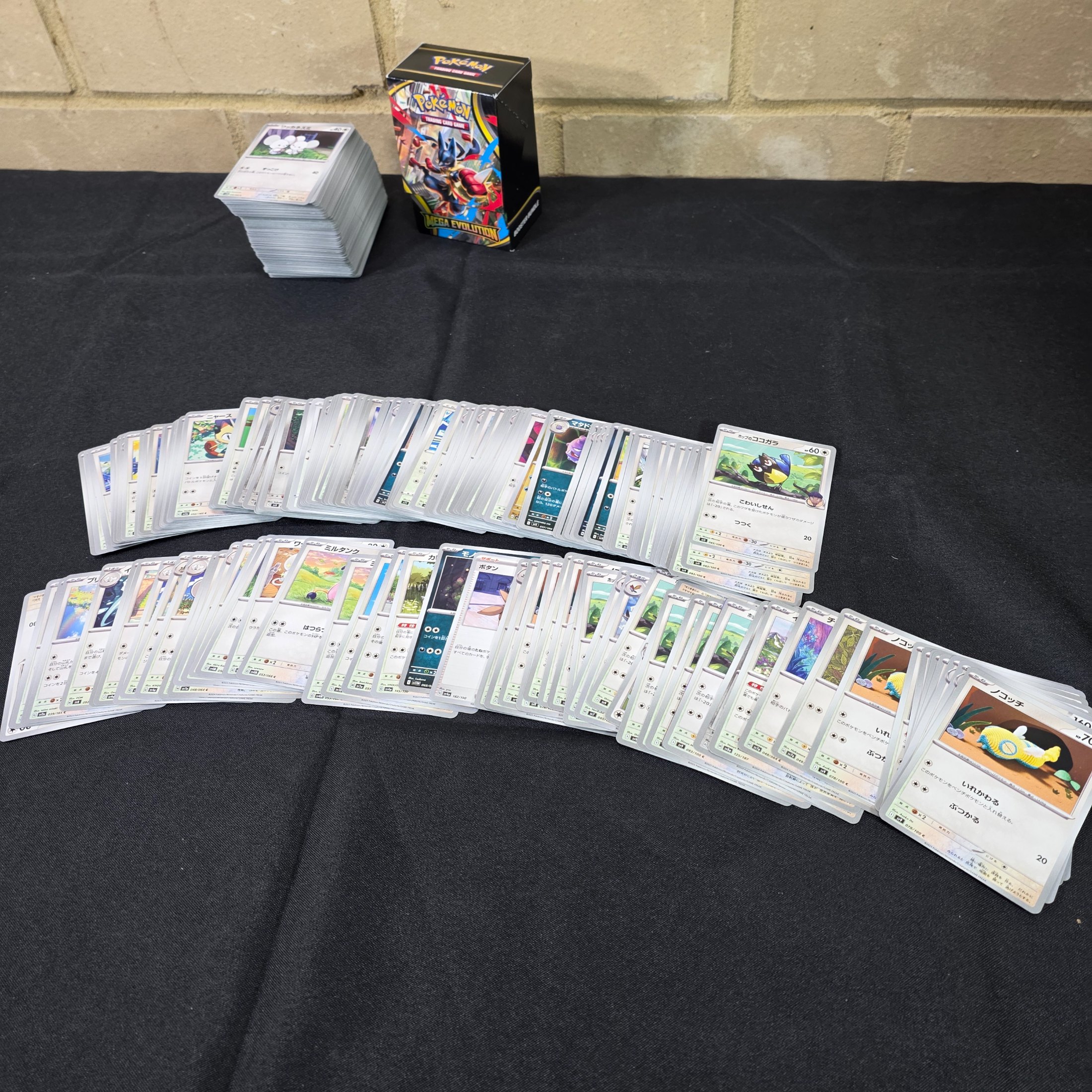 A collection of Japanese Pokémon Trading Card Game cards, including a "Mega Evolution" themed box and multiple stacks of cards. - View 5