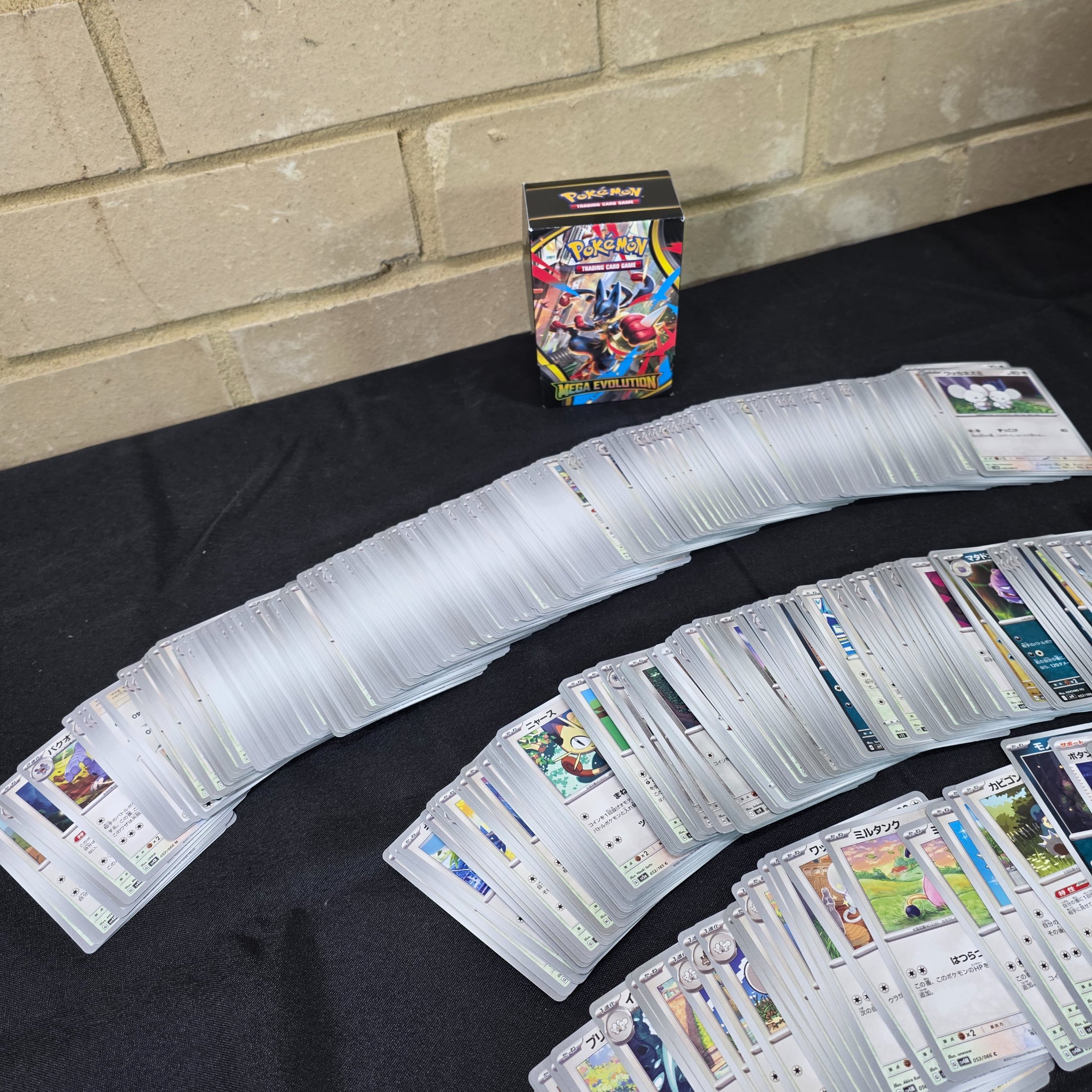 A collection of Japanese Pokémon Trading Card Game cards, including a "Mega Evolution" themed box and multiple stacks of cards. - View 6