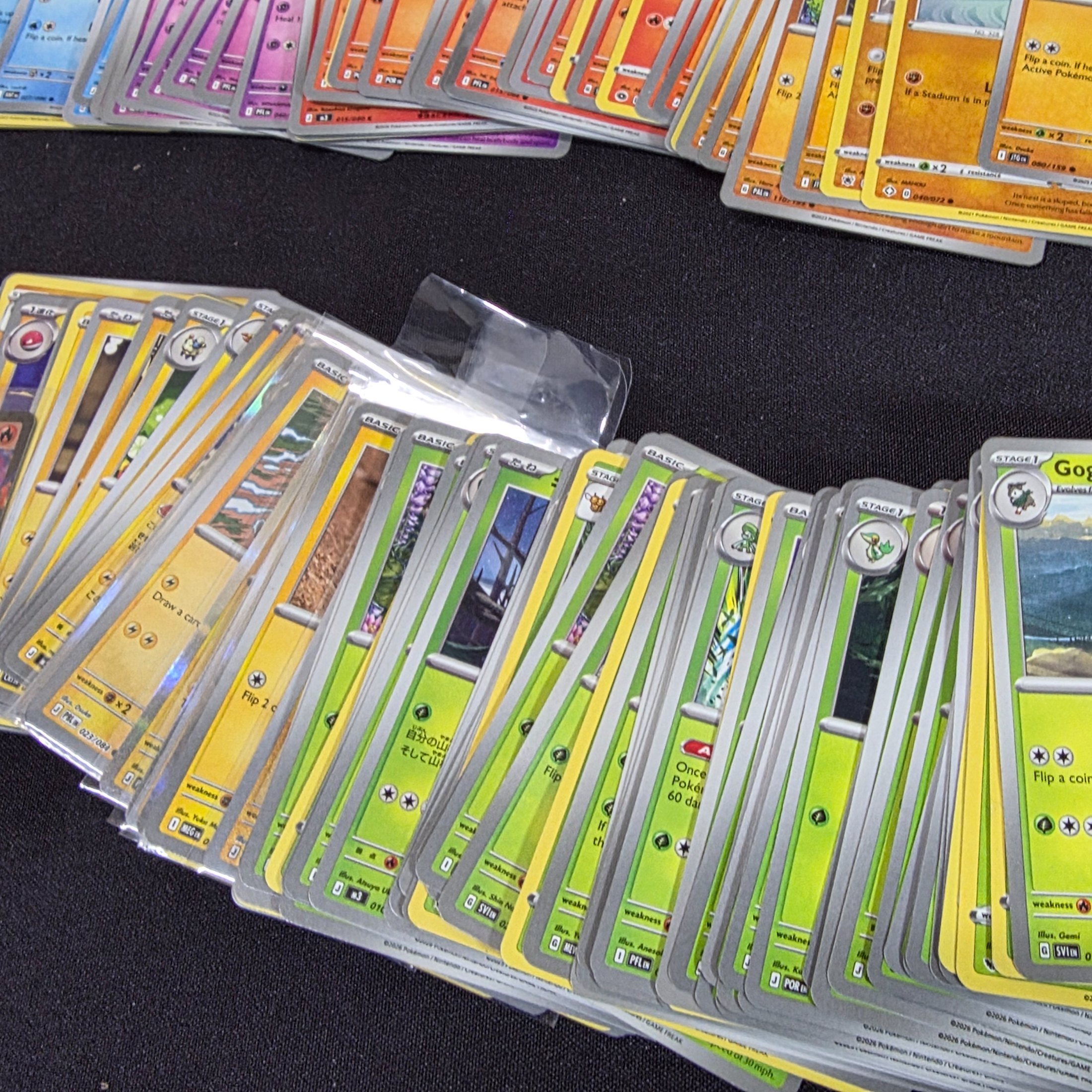 A large collection of Japanese and English Pokemon trading cards, featuring a diverse range of characters and card types spread across a black surface. - View 4