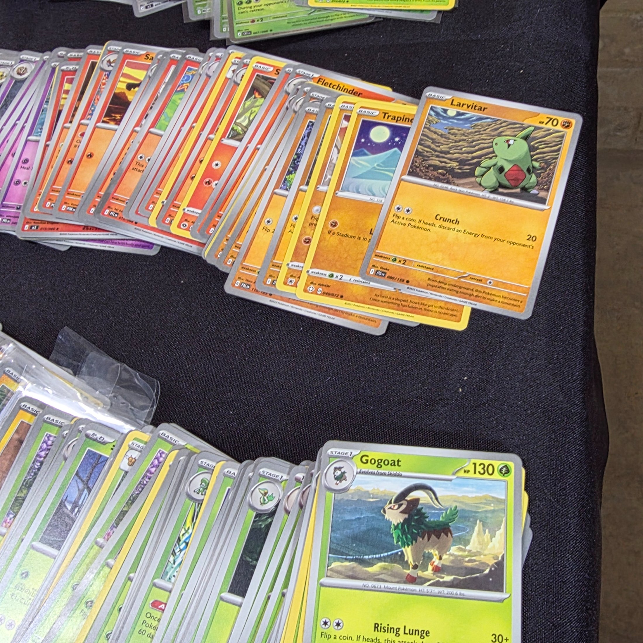 A large collection of Japanese and English Pokemon trading cards, featuring a diverse range of characters and card types spread across a black surface. - View 5
