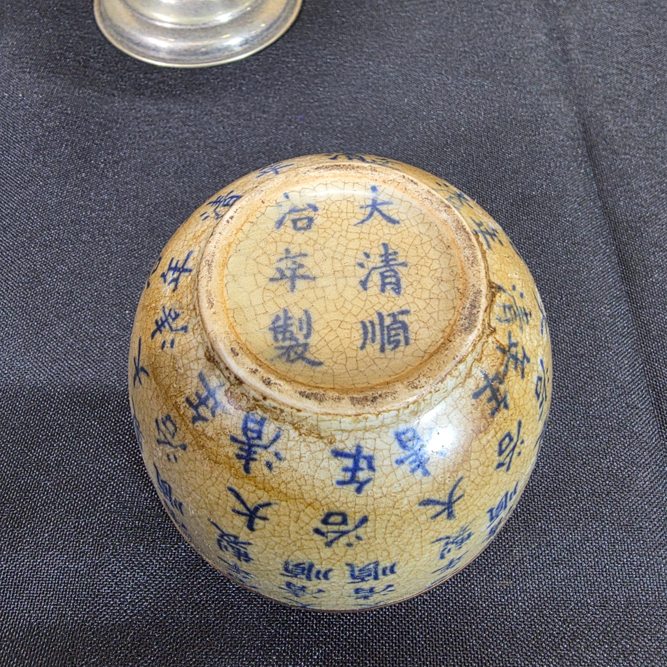 A diverse lot of antique and vintage items, including a rusty cast iron flat iron, a silver-plated bowl with a cobalt blue glass insert holding decorative painted eggs, and a Chinese crackle-glazed ceramic lidded jar with blue characters. - View 6