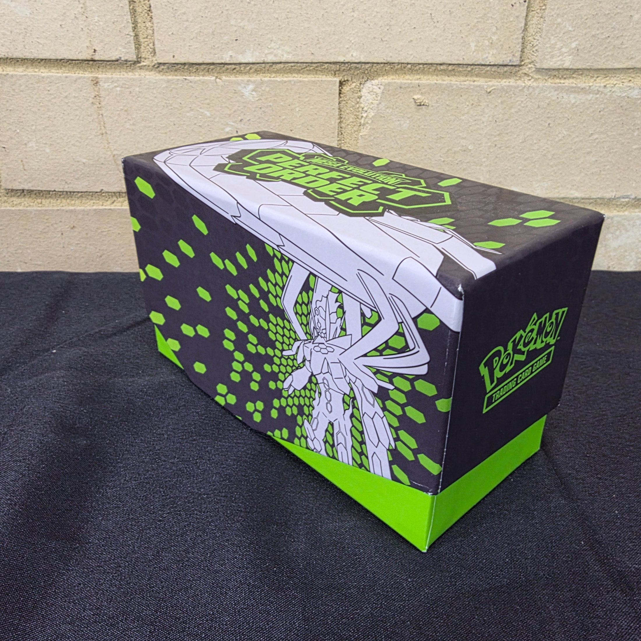A green and black Pokémon Trading Card Game 'Perfect Order' storage box filled with assorted bulk cards.