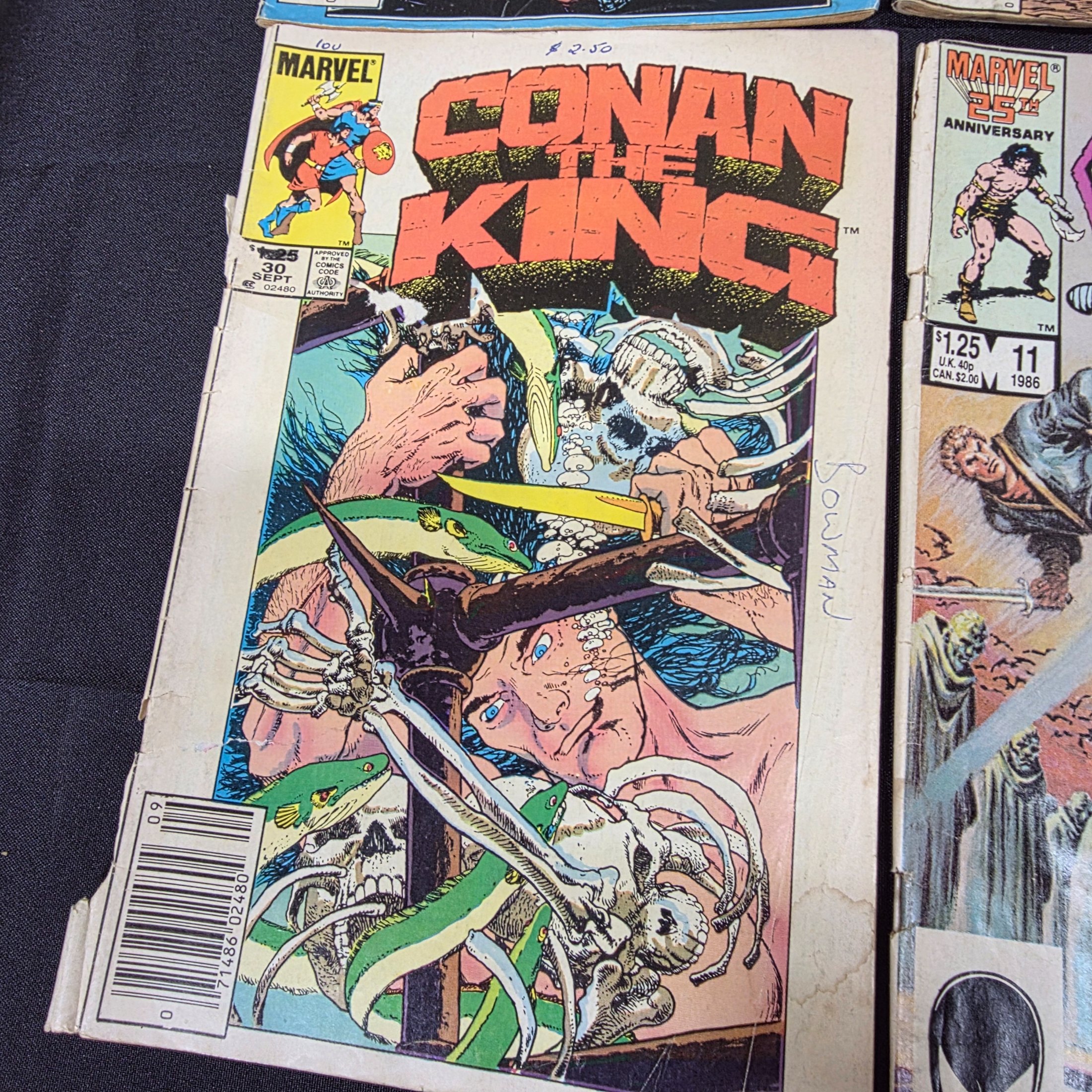 A collection of vintage Marvel 'Conan the King' and 'Conan the Barbarian' comic books from the 1980s, displayed on a black surface against a brick wall. - View 3