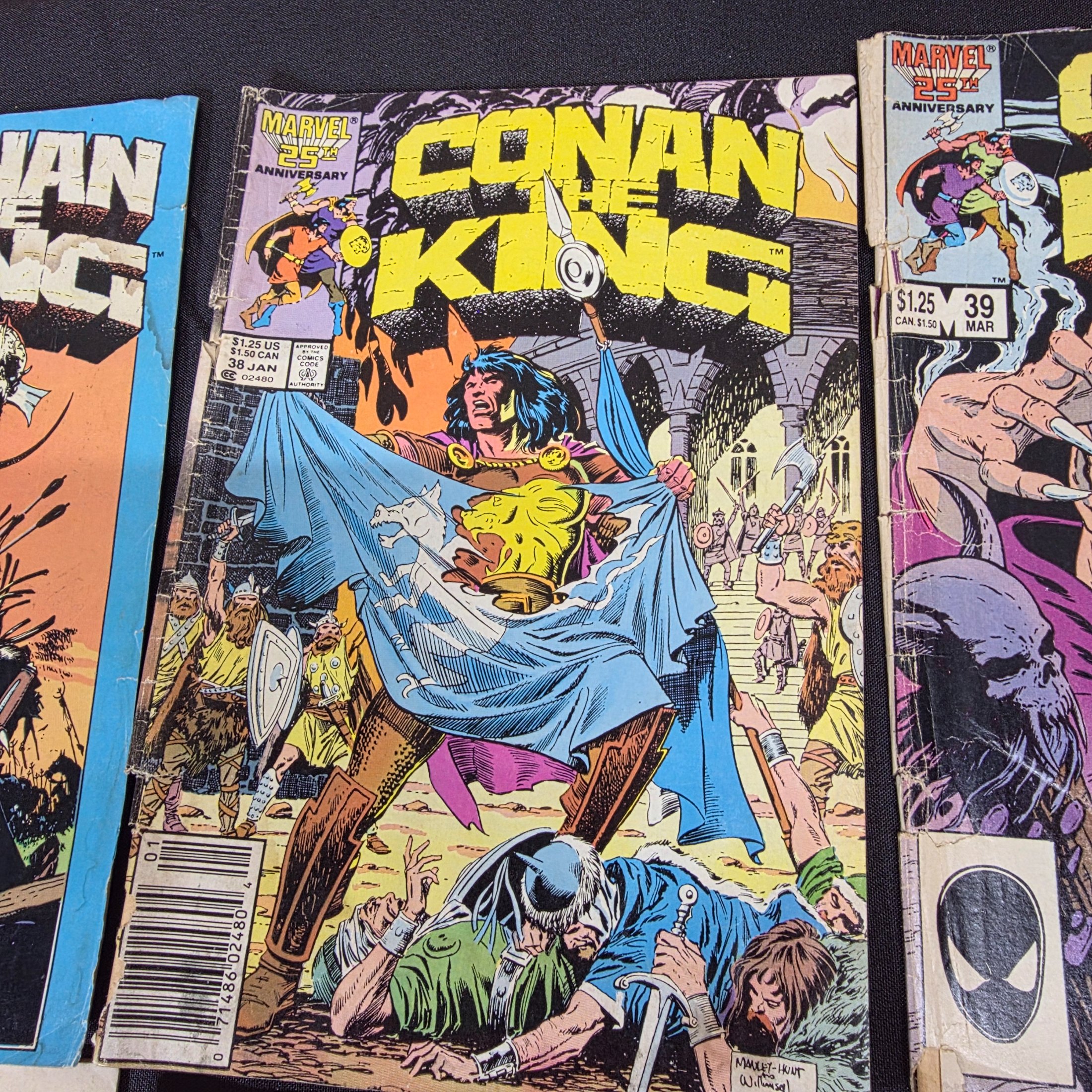 A collection of vintage Marvel 'Conan the King' and 'Conan the Barbarian' comic books from the 1980s, displayed on a black surface against a brick wall. - View 4