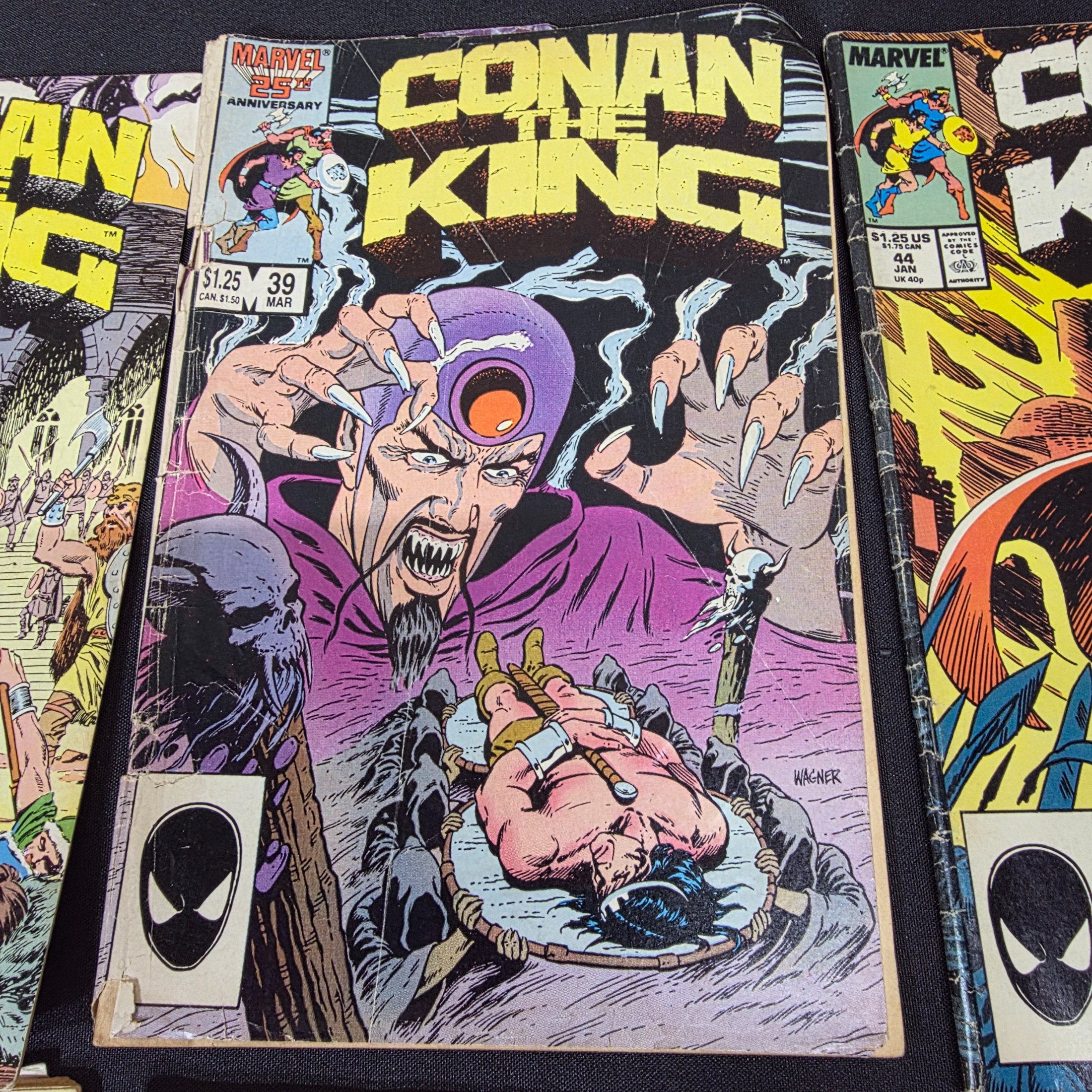 A collection of vintage Marvel 'Conan the King' and 'Conan the Barbarian' comic books from the 1980s, displayed on a black surface against a brick wall. - View 6