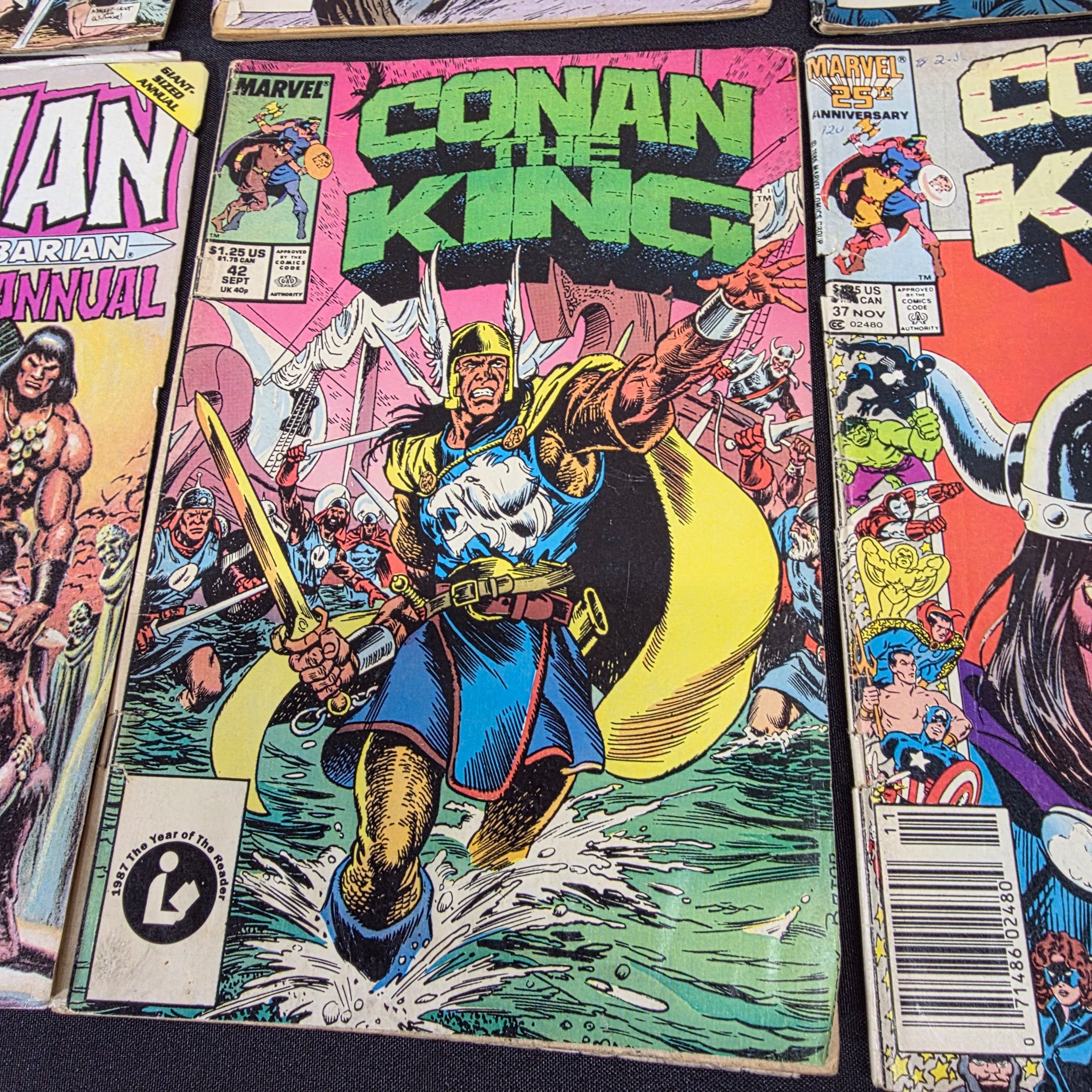 A collection of vintage Marvel 'Conan the King' and 'Conan the Barbarian' comic books from the 1980s, displayed on a black surface against a brick wall. - View 7