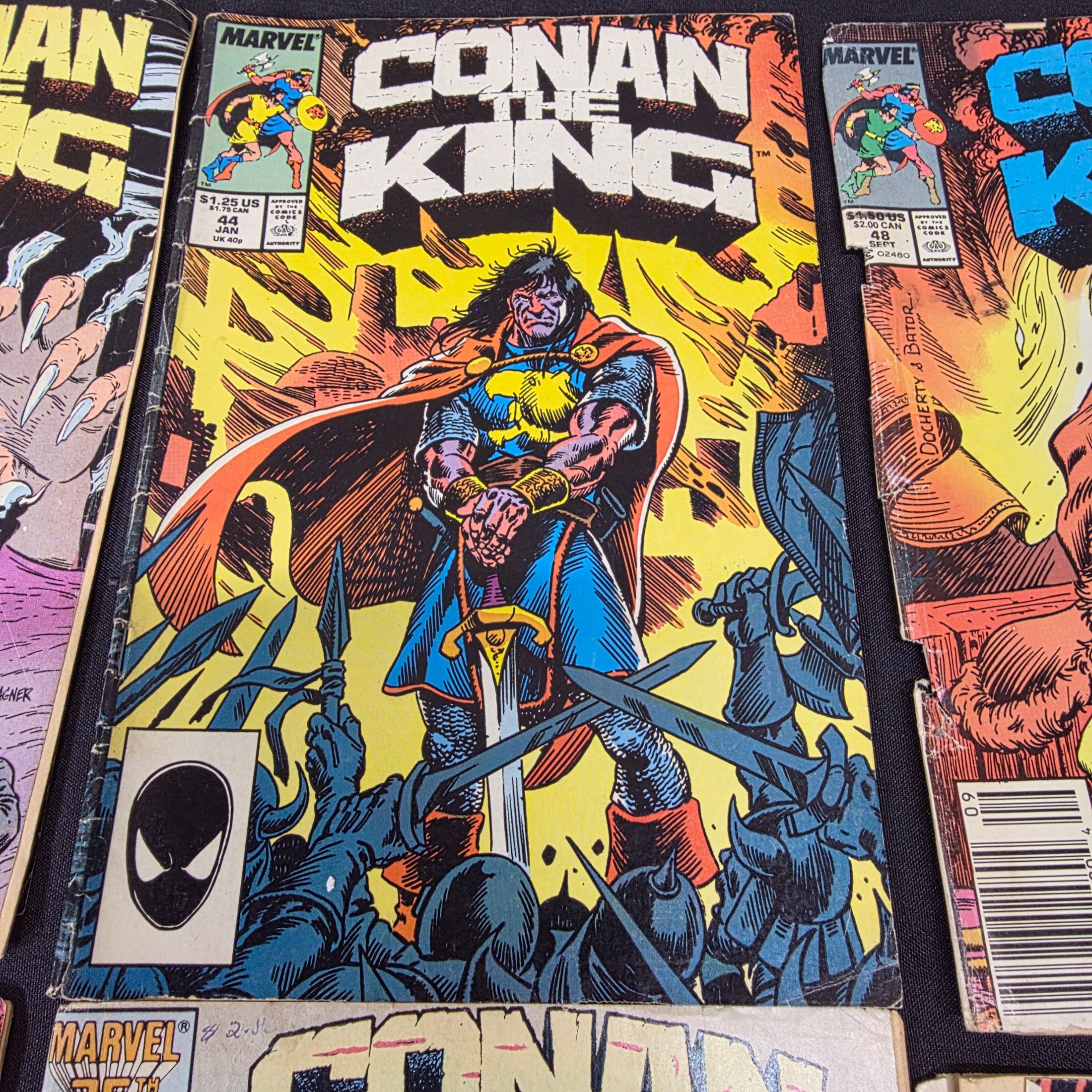 A collection of vintage Marvel 'Conan the King' and 'Conan the Barbarian' comic books from the 1980s, displayed on a black surface against a brick wall. - View 8