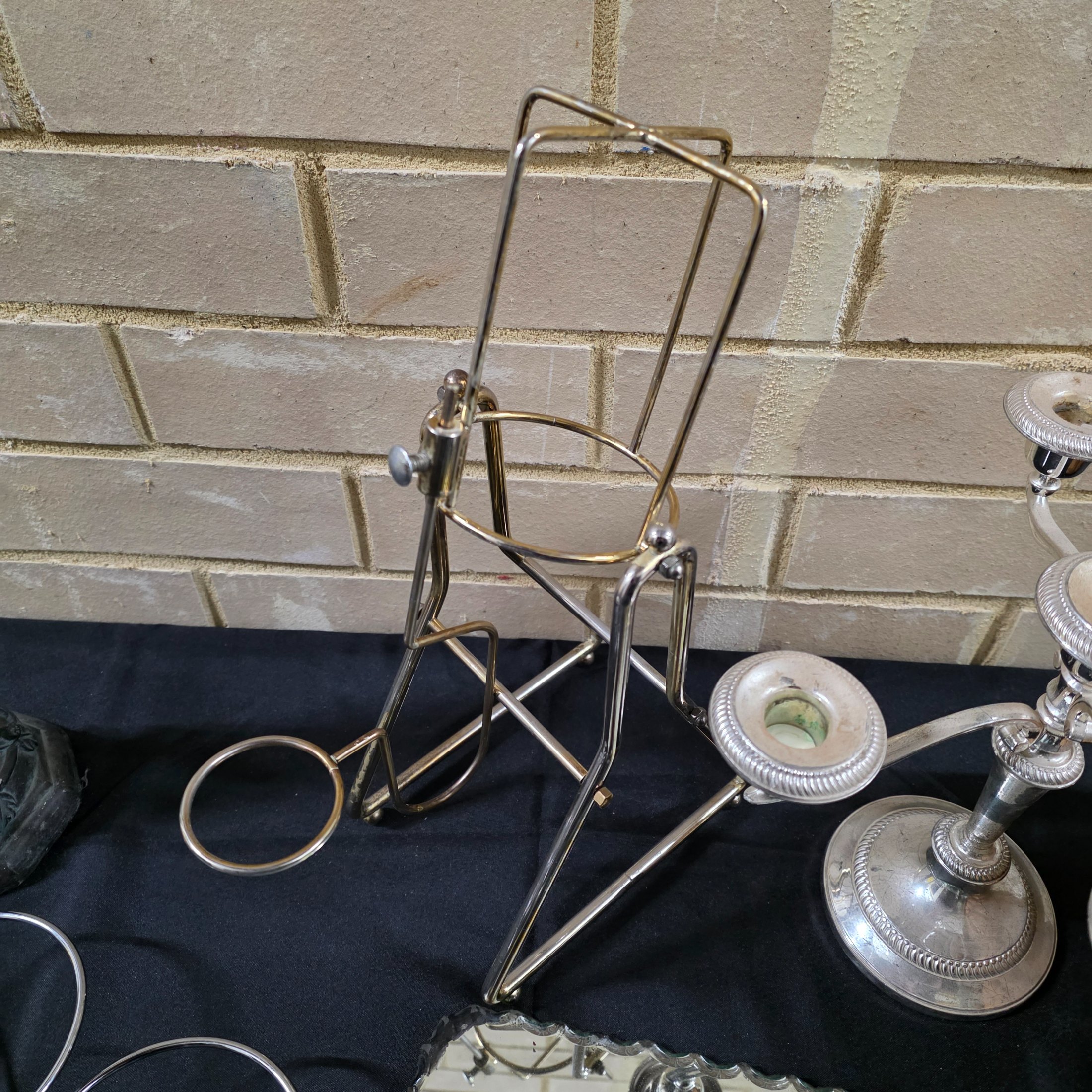 A varied collection of vintage homewares featuring a dark metal candlestick, a silver-plated candelabra, a mirrored tray, and several other decorative and functional pieces. - View 5