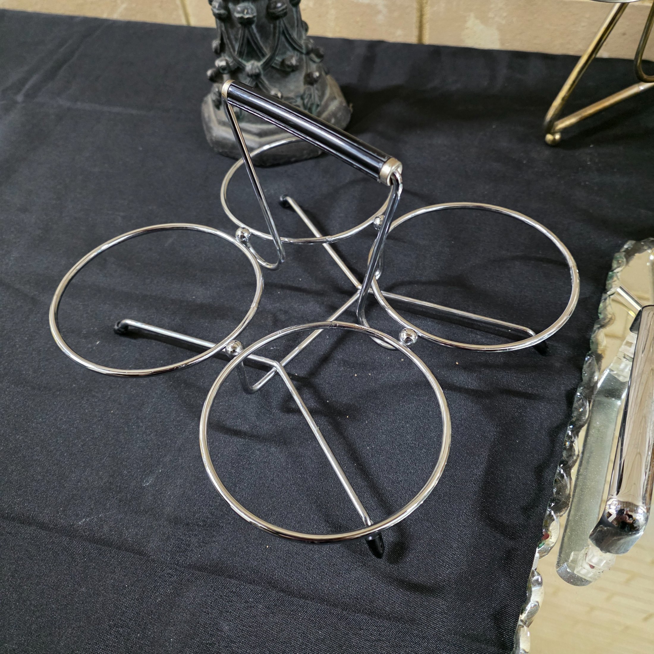A varied collection of vintage homewares featuring a dark metal candlestick, a silver-plated candelabra, a mirrored tray, and several other decorative and functional pieces. - View 6