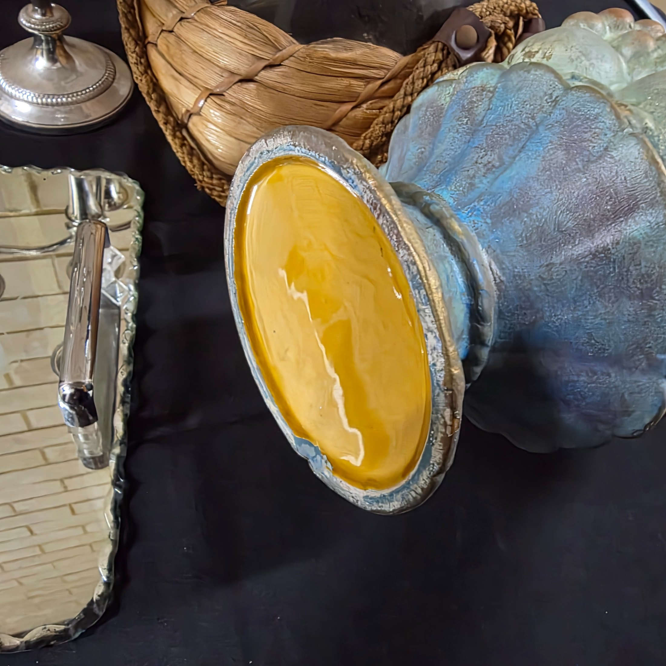 A varied collection of vintage homewares featuring a dark metal candlestick, a silver-plated candelabra, a mirrored tray, and several other decorative and functional pieces. - View 8