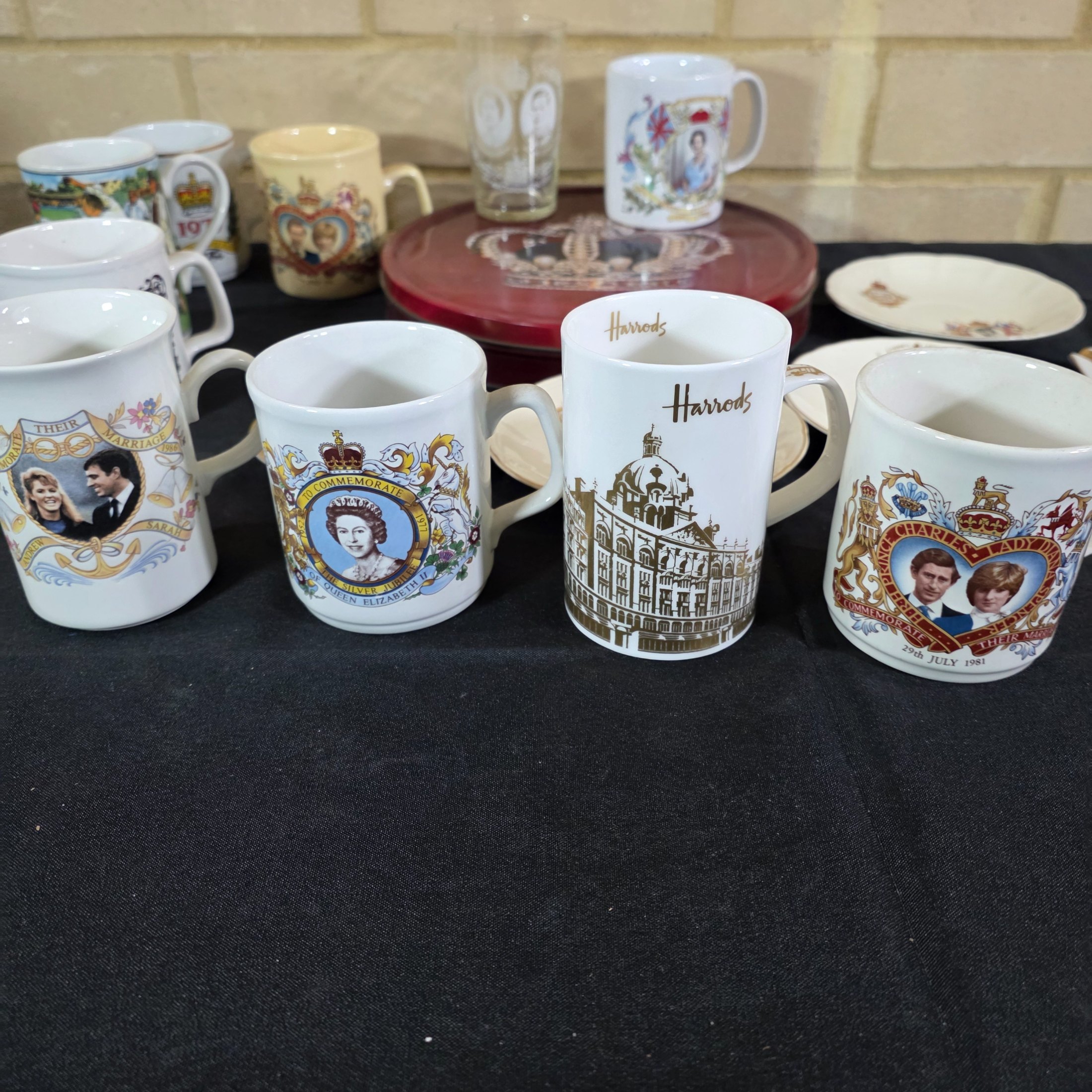 A diverse collection of commemorative ceramics, decorative mugs, and various household sundries from the mid to late 20th century, including royal memorabilia, novelty mugs, a vintage wax jar, and a tea tin. - View 5