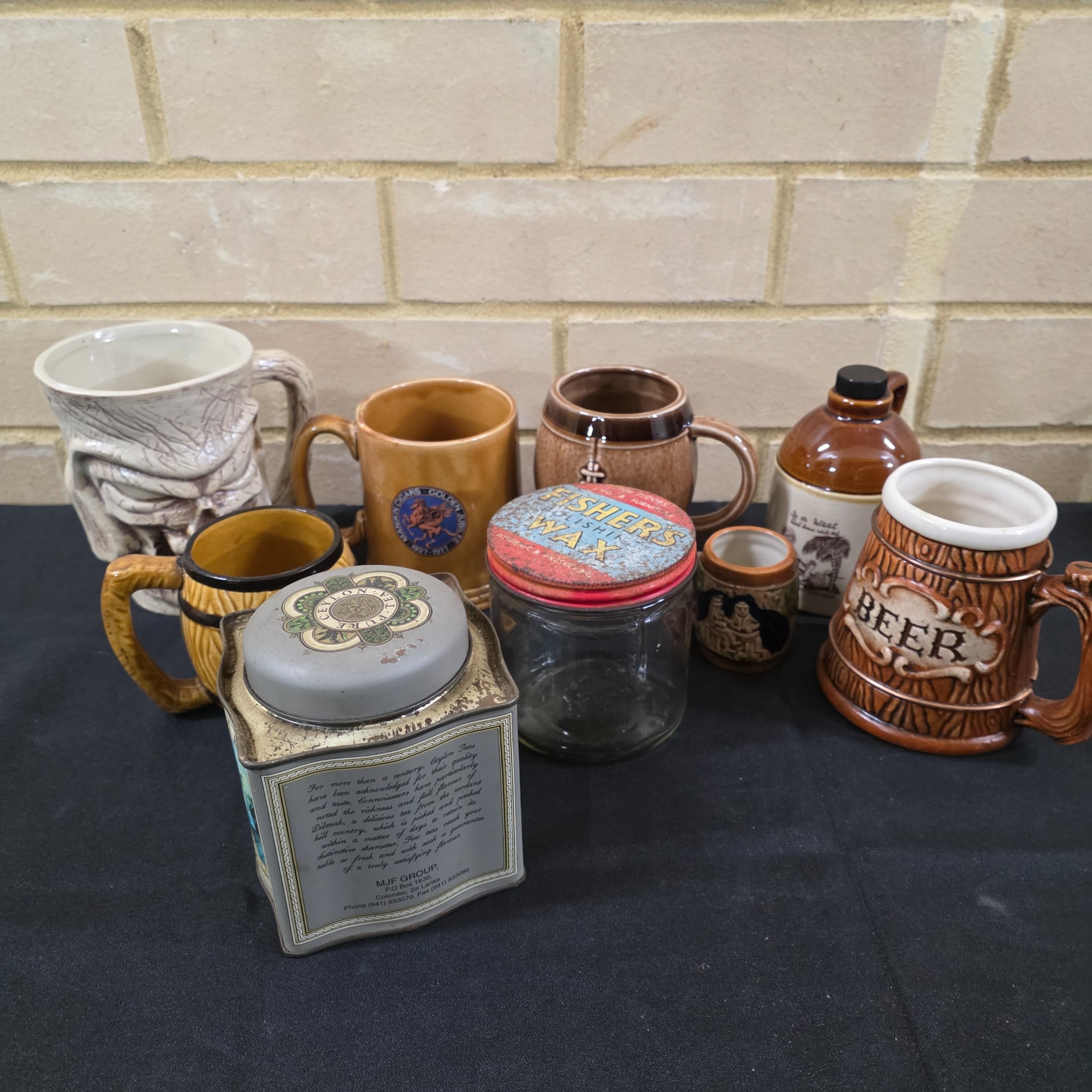 A diverse collection of commemorative ceramics, decorative mugs, and various household sundries from the mid to late 20th century, including royal memorabilia, novelty mugs, a vintage wax jar, and a tea tin. - View 7