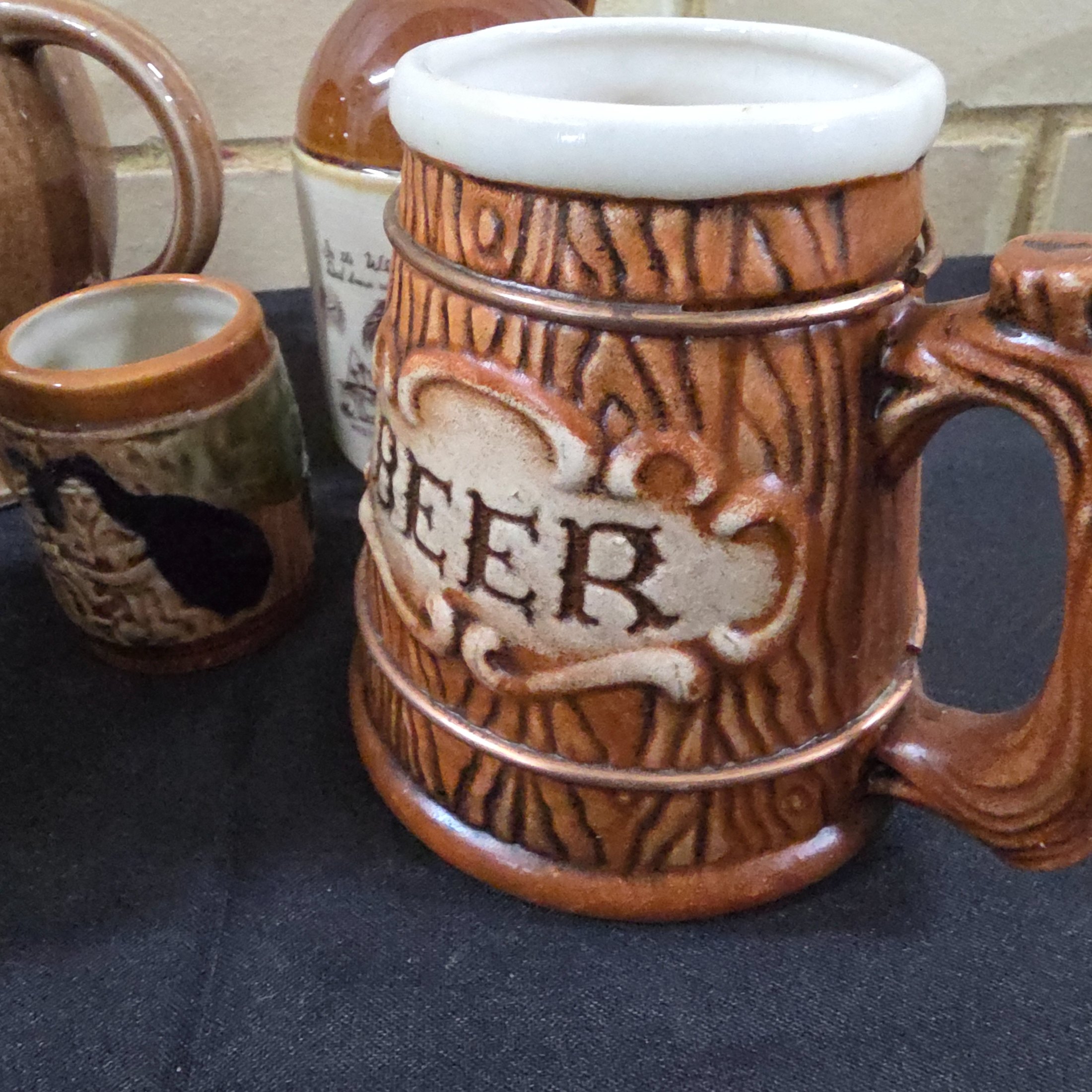 A diverse collection of commemorative ceramics, decorative mugs, and various household sundries from the mid to late 20th century, including royal memorabilia, novelty mugs, a vintage wax jar, and a tea tin. - View 8