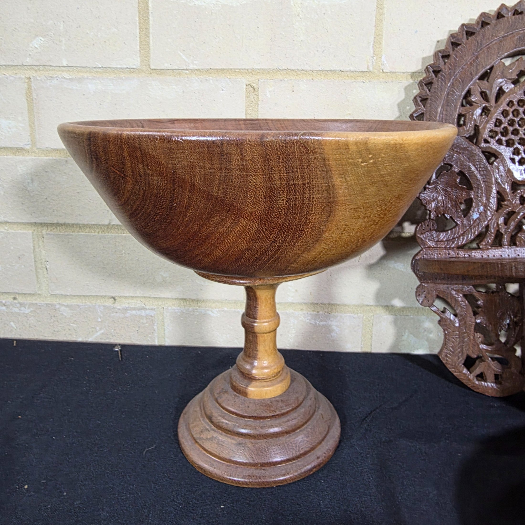 A collection of vintage wooden homewares including a pedestal bowl, lidded container, carved monkey figure, candlestick, wall shelf, and a round trivet. - View 2