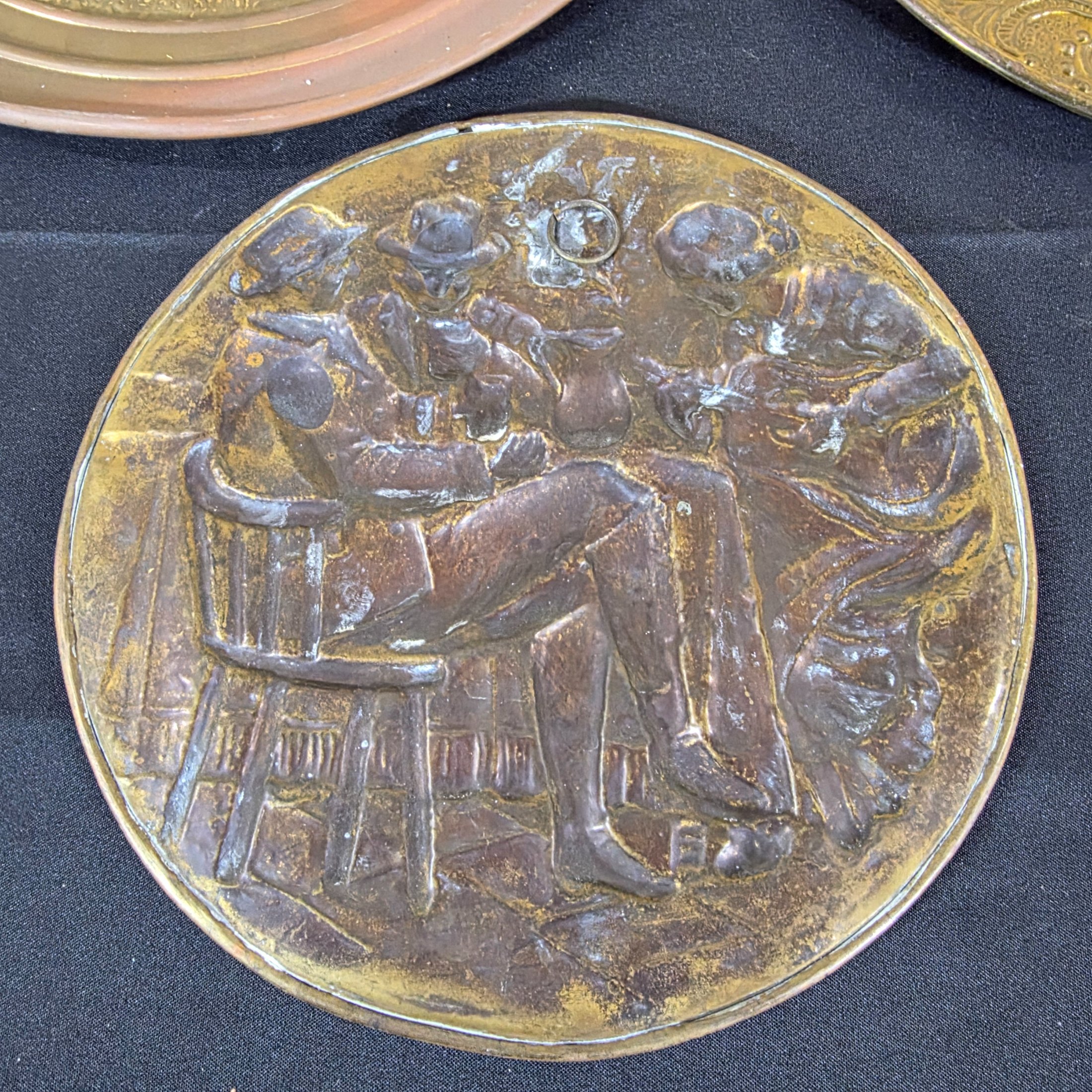 A collection of four vintage embossed metal wall plaques, comprising a large copper-toned plaque featuring a portrait of Peter Paul Rubens, two brass-toned plaques depicting fox hunting and horse-drawn carriage scenes, and a smaller copper-toned plaque with a tavern scene. - View 8
