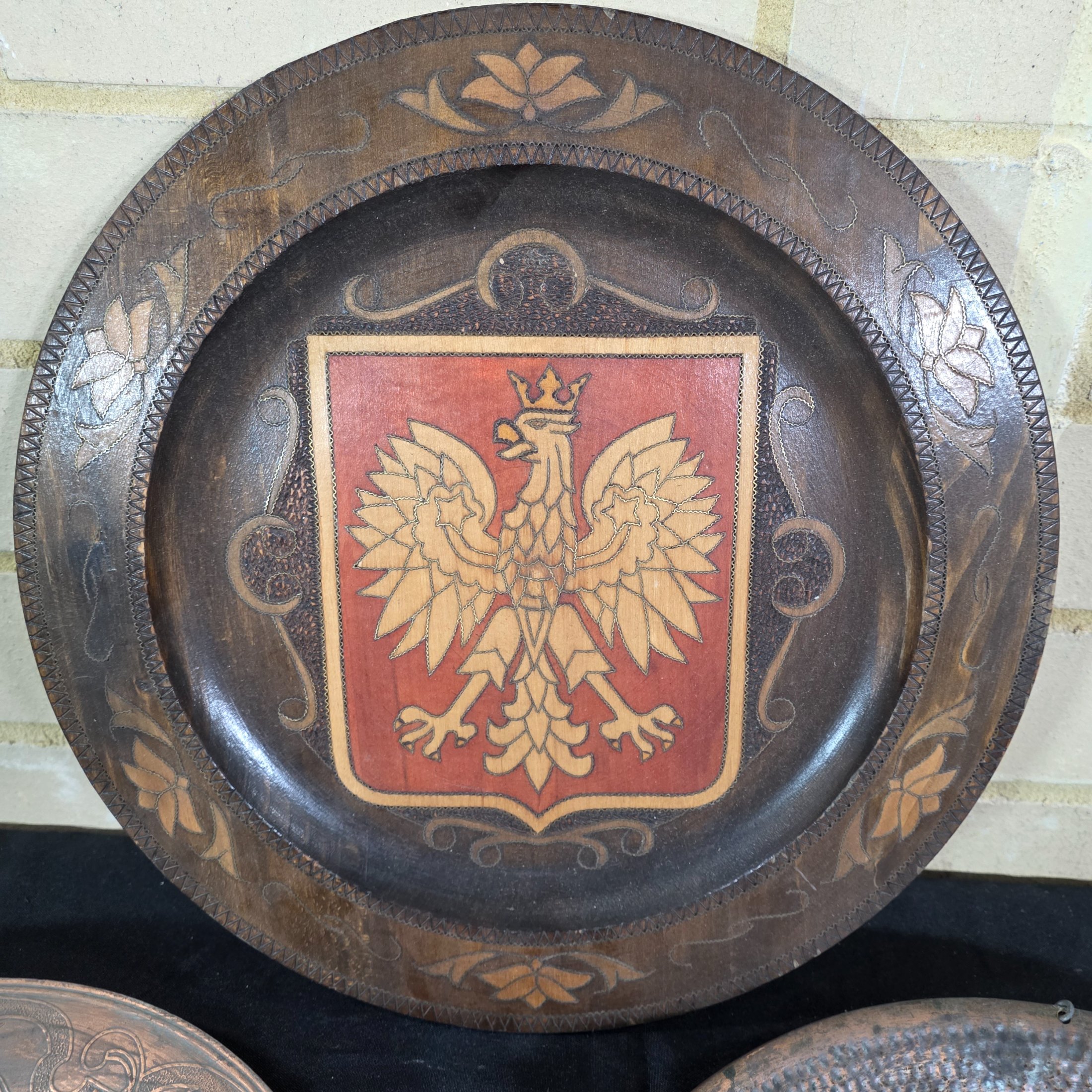 A collection of three vintage decorative wall plates, including a wooden plate with a Polish eagle crest and two copper or bronze plates featuring classical hunting and musical figures. - View 2