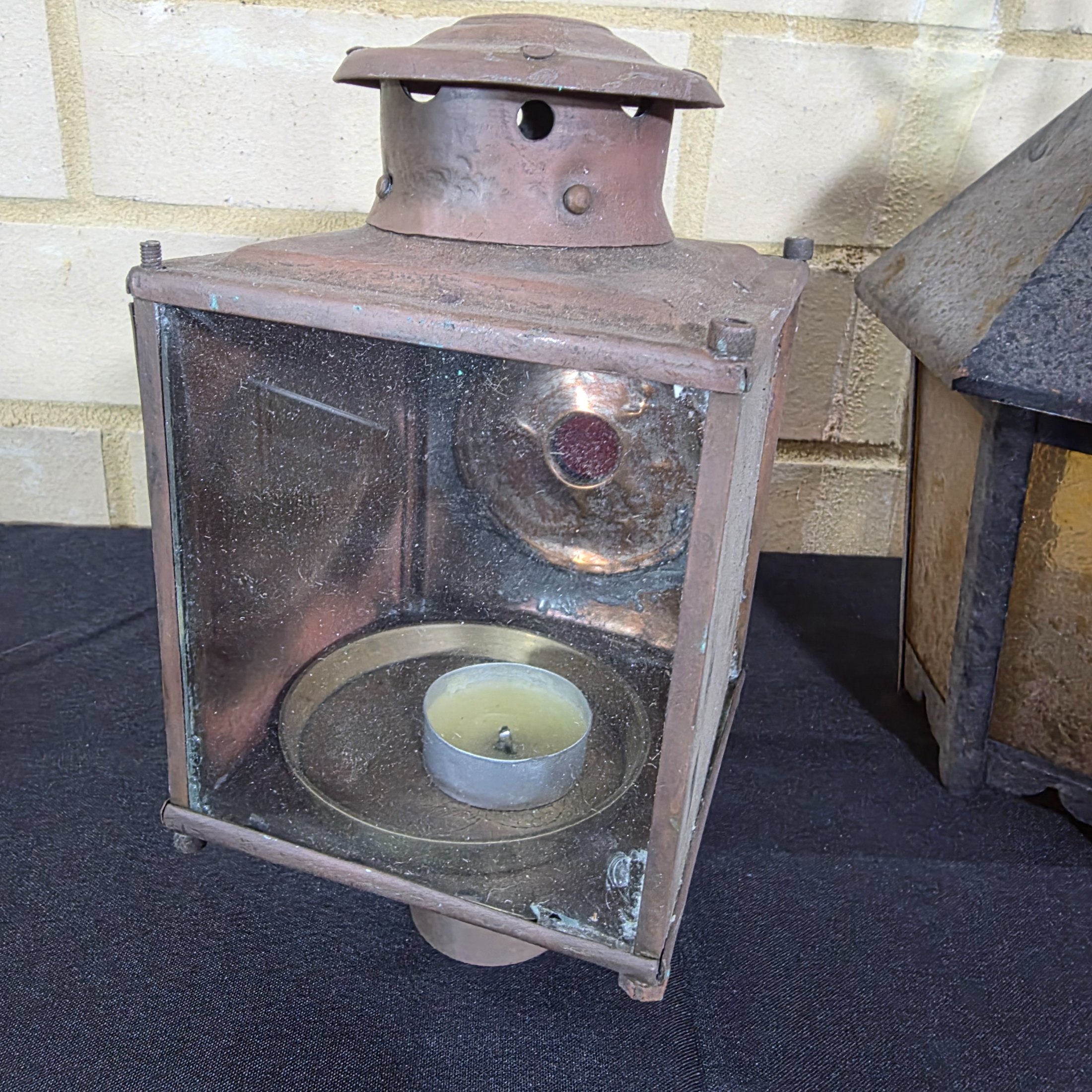 A diverse lot of three vintage outdoor lanterns, comprising a green wall-mounted electric light, an older copper-toned candle lantern, and a black painted Kempthorne electric wall sconce with amber glass. - View 7