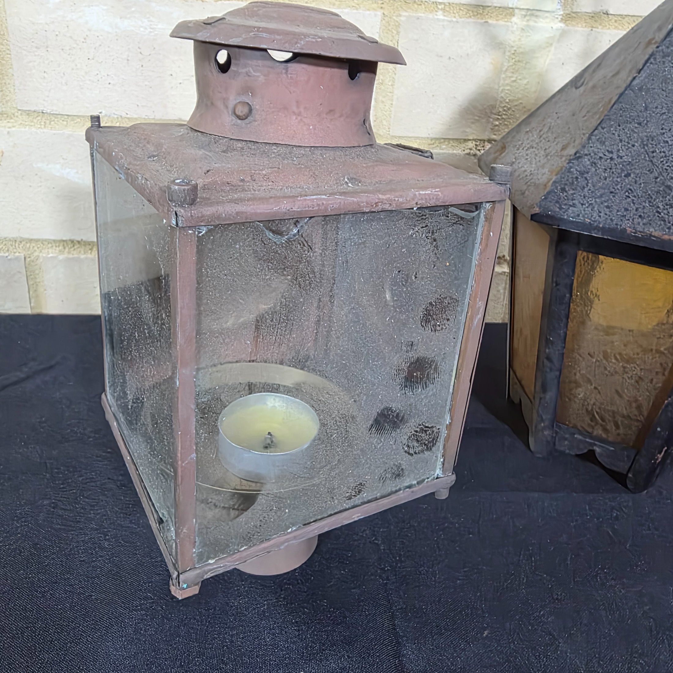A diverse lot of three vintage outdoor lanterns, comprising a green wall-mounted electric light, an older copper-toned candle lantern, and a black painted Kempthorne electric wall sconce with amber glass. - View 8