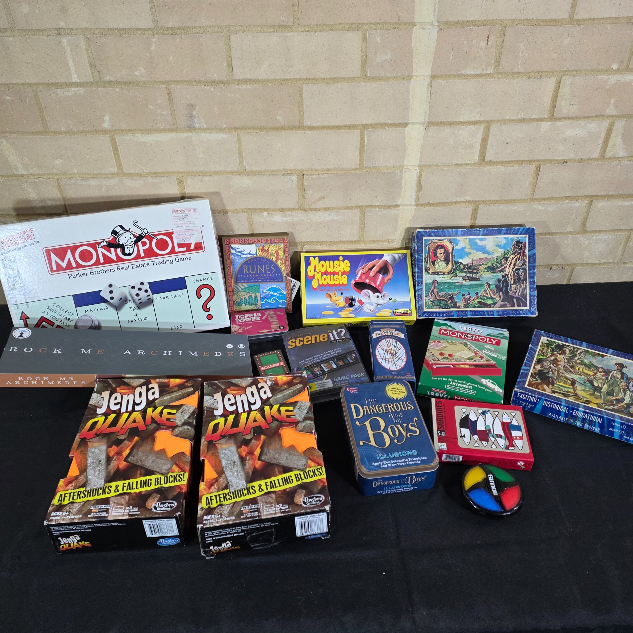 A diverse collection of modern and vintage board games, card games, and puzzles, including Monopoly, Jenga Quake, Mousie Mousie, and a Captain Cook's Voyage puzzle.