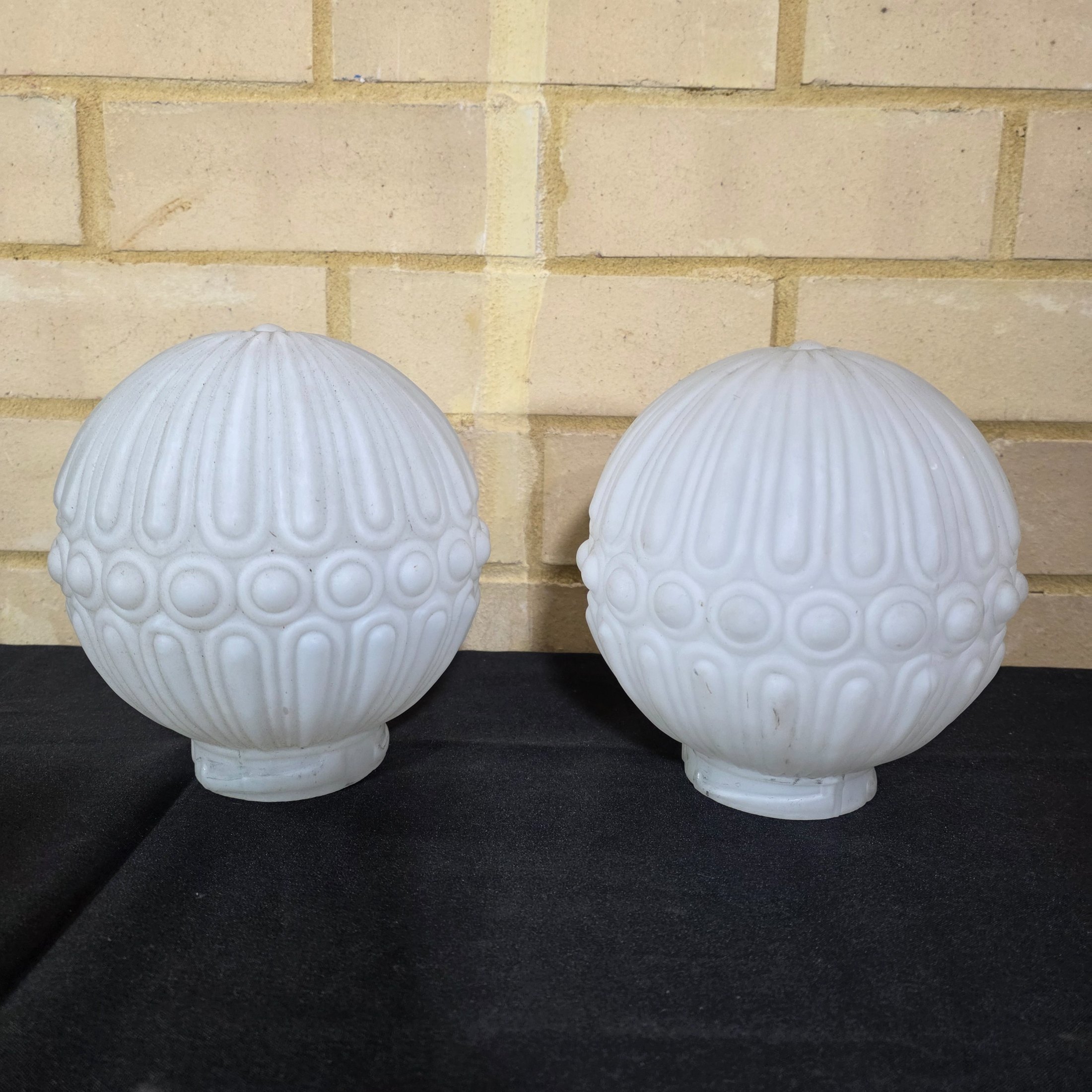 A pair of elegant mid-20th century frosted glass light shades, featuring a distinctive ribbed and raised circular motif, suitable for decorative lighting.