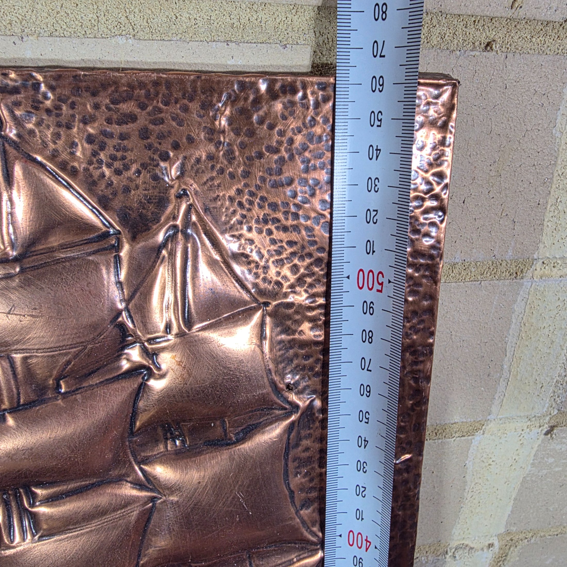 A collection of three vintage embossed metal decorative items, including a rectangular copper wall hanging and two round plates, all depicting sailing ships. - View 8