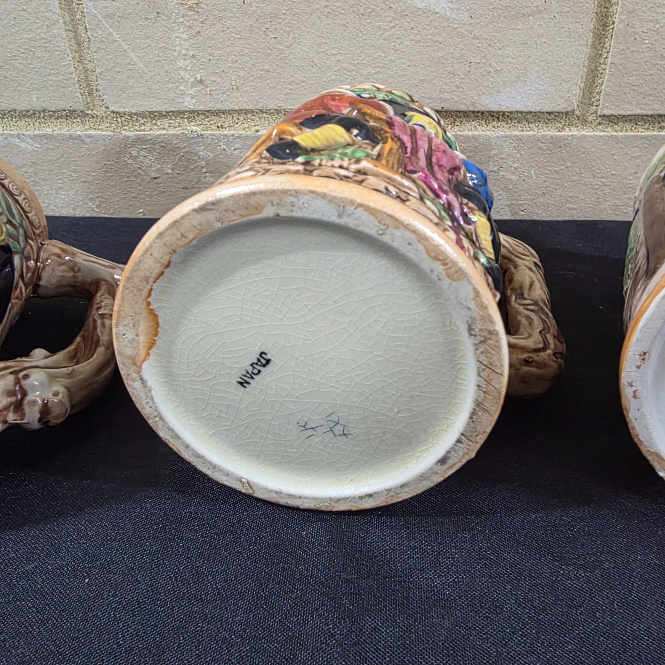 A set of four vintage Japanese ceramic mugs, designed in the style of traditional German beer steins, featuring intricate, hand-painted raised relief scenes depicting various Bavarian-themed activities and figures. - View 7