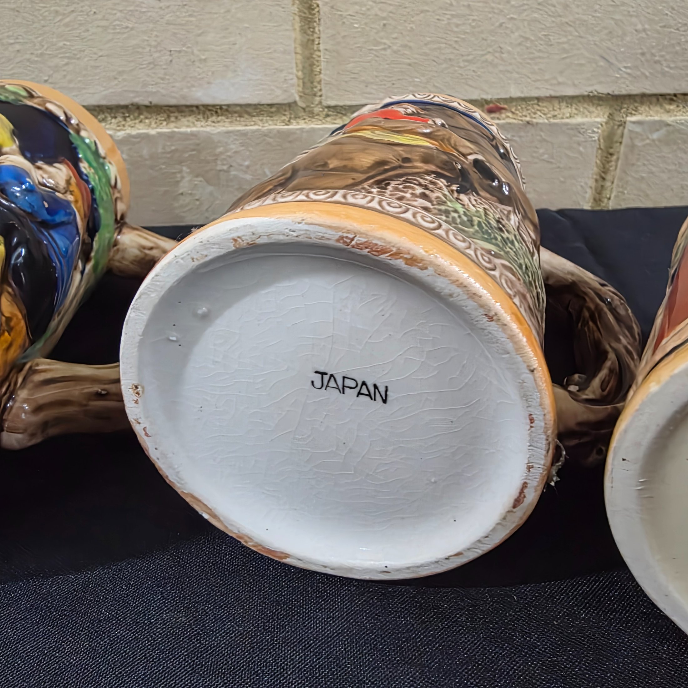 A set of four vintage Japanese ceramic mugs, designed in the style of traditional German beer steins, featuring intricate, hand-painted raised relief scenes depicting various Bavarian-themed activities and figures. - View 8