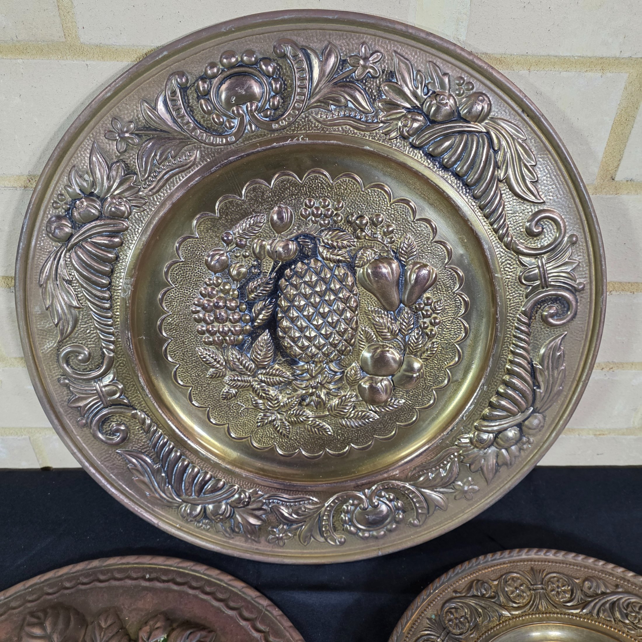 A set of three vintage decorative wall plaques, featuring embossed fruit designs in brass and copper-toned metal. - View 2